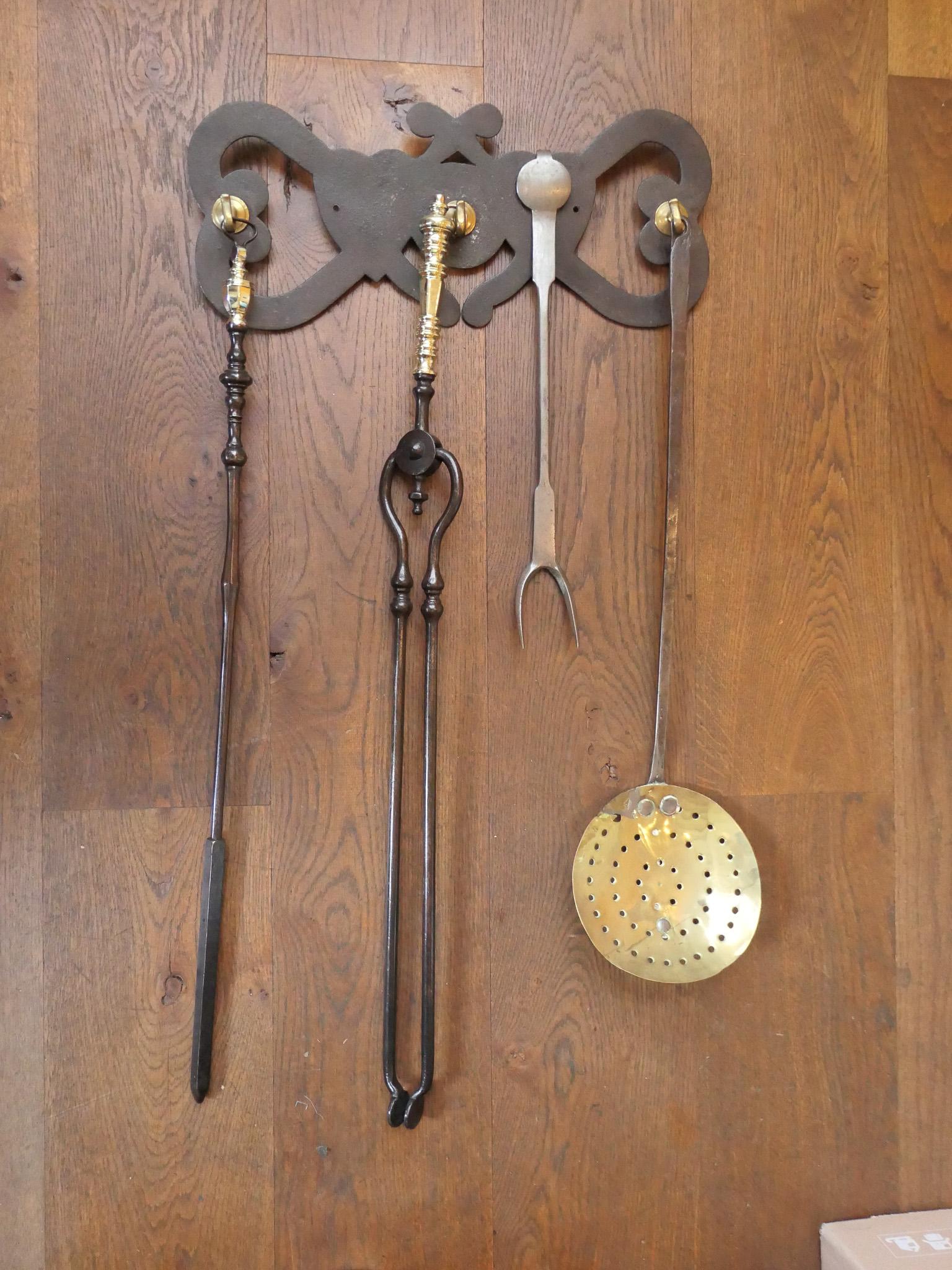 18th - 19th century Dutch neoclassical fireplace tool set consisting of a fireplace tongs, fire poker, a tasting fork and a skimmer and a hanger. The set is also made of wrought iron and some brass. They are in a good condition and are fully