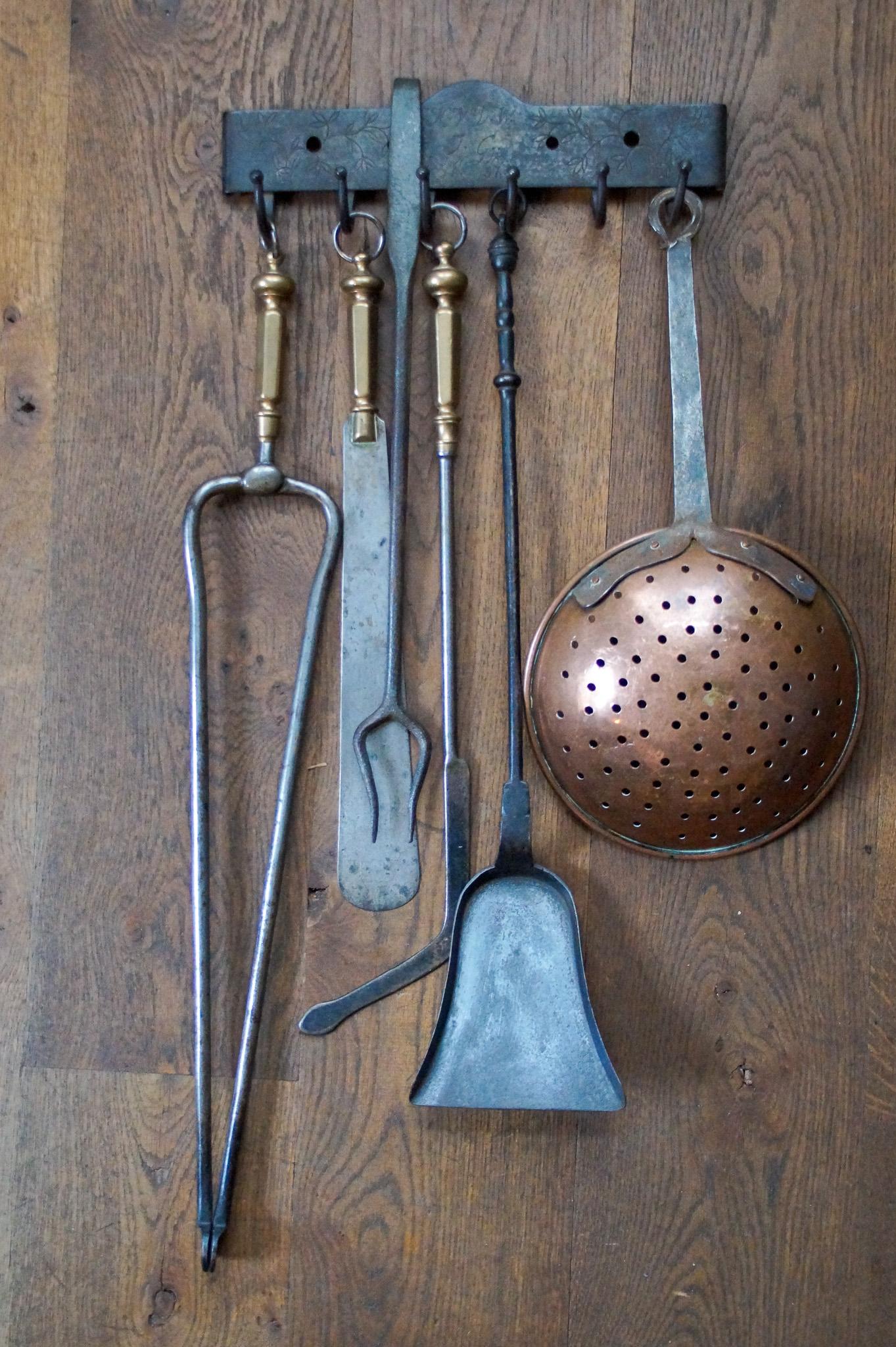 19th century Dutch victorian fireplace tool set consisting of a fireplace tongs, a tasting fork, a skimmer, a shovel, a spatula, a fire poke and a hanger. The set is made of wrought iron, three tools have a bronze handle and the skimmer is made of