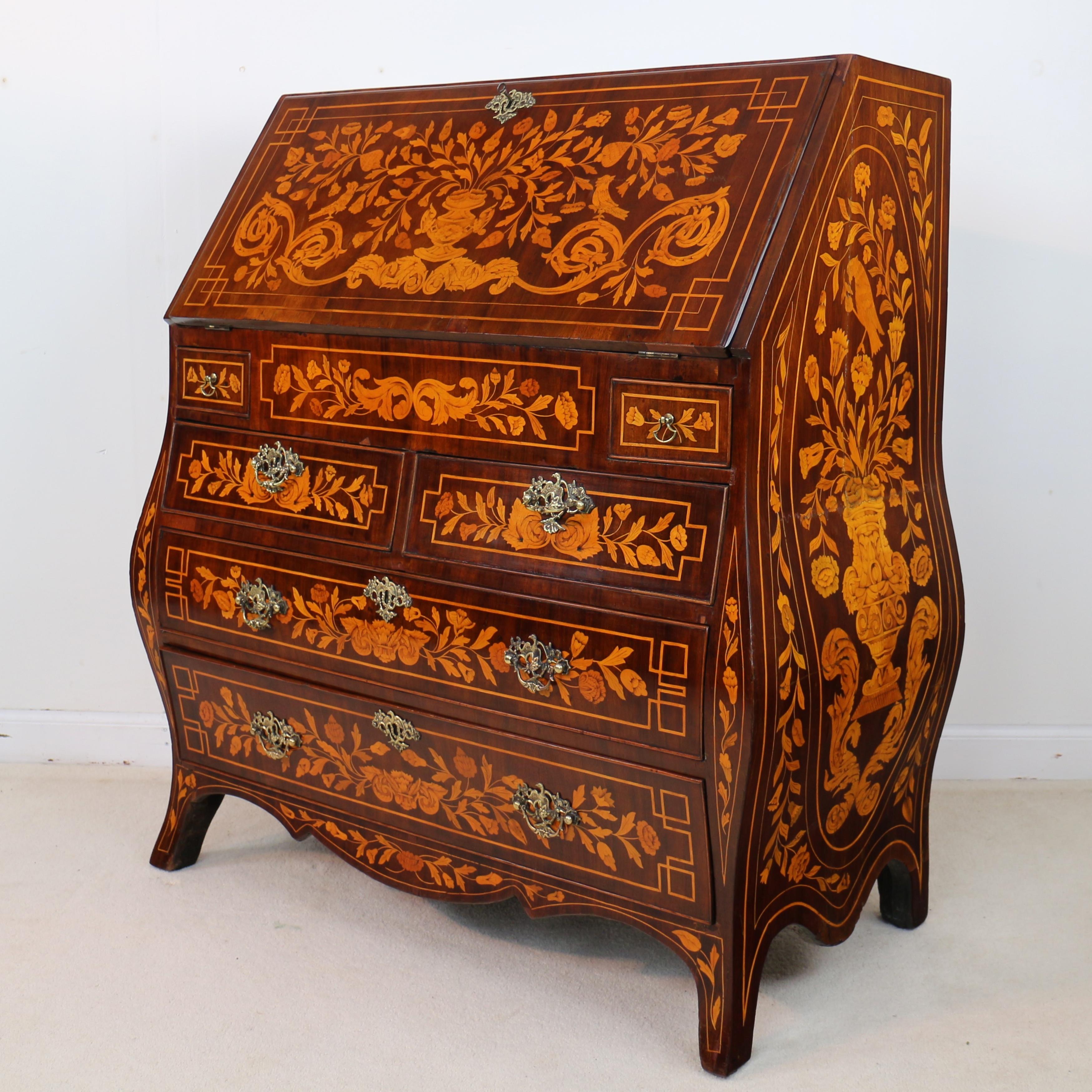 A 19th century Dutch marquetry inlaid bombé bureau profusely decorated all-over with marquetry depictions of flowers, urns and birds. With a rectangular flap opening to reveal a striking floral marquetry stepped fitted interior with a well, two
