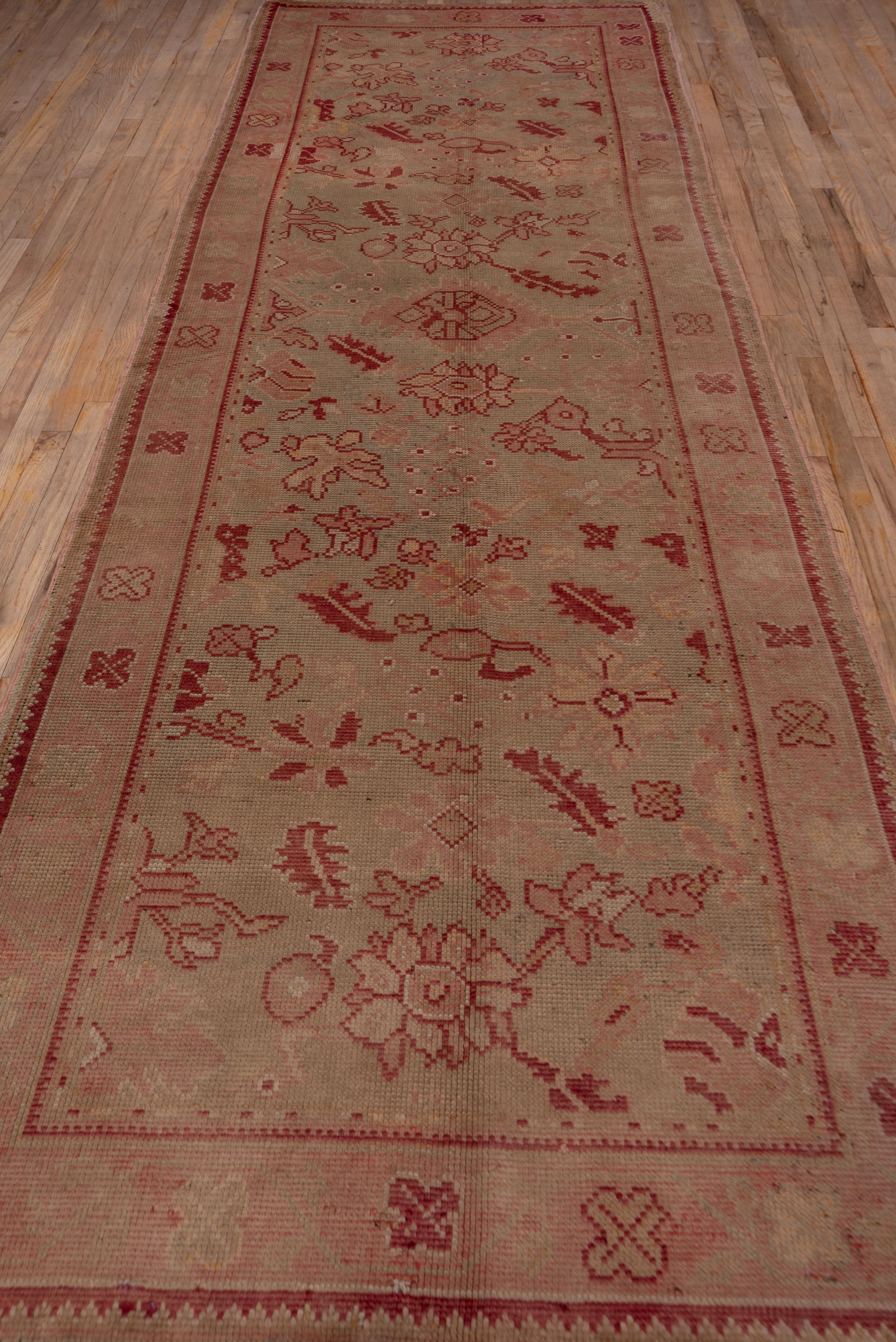 This antique Dutch gallery carpet has a Persian Harshang palmette, leaf and flower pattern has been fragmented and rearranged on the sand ground, with accents in buff, light brown and beige. Simple ragged palmettes accent the center line of the