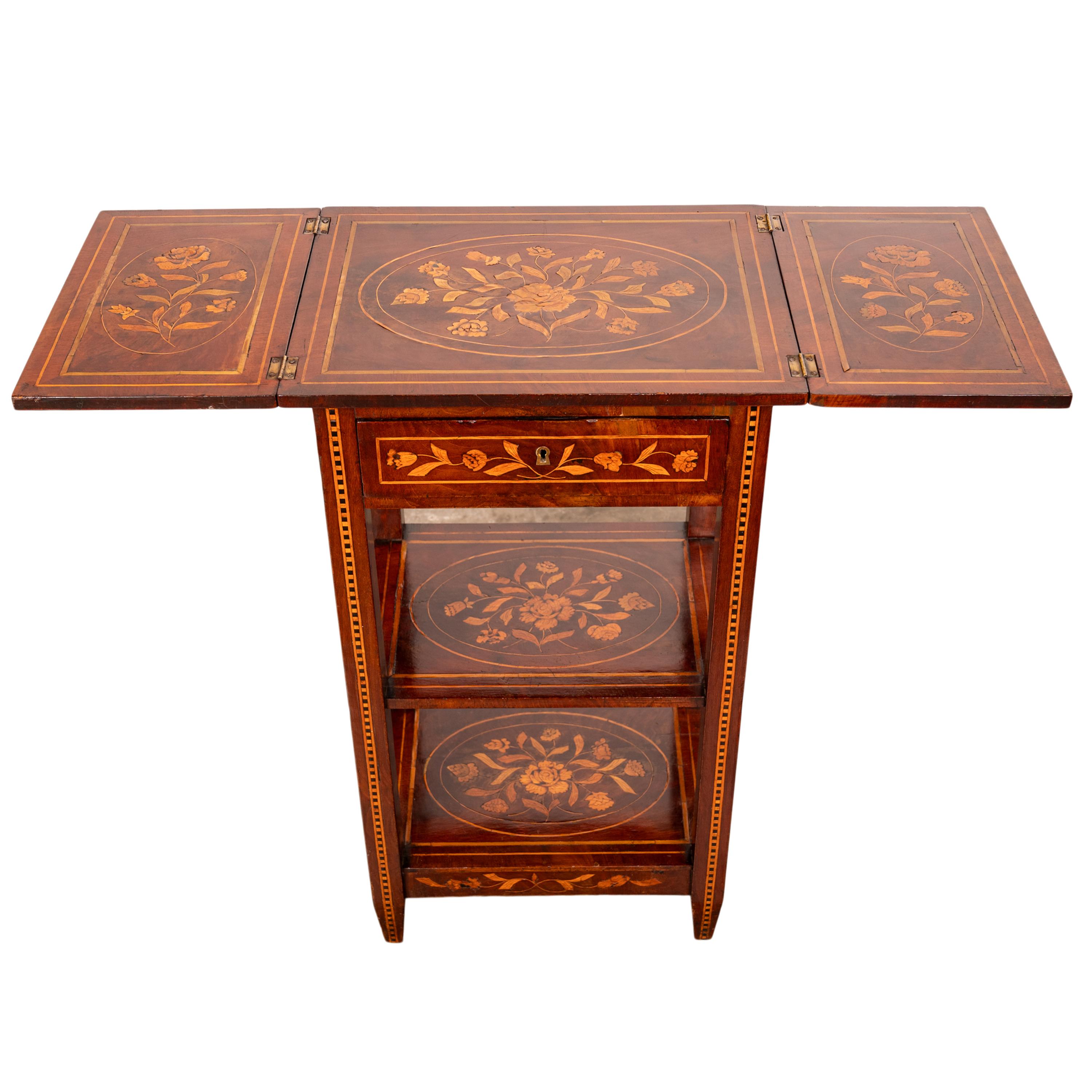 Table d'appoint en marqueterie hollandaise de bois de rose, vers 1820.
Cette table/étagère très élégante et rare a un plateau dépliable, les feuilles une fois fermées ont une somptueuse marqueterie incrustée de deux urnes fleuries avec des