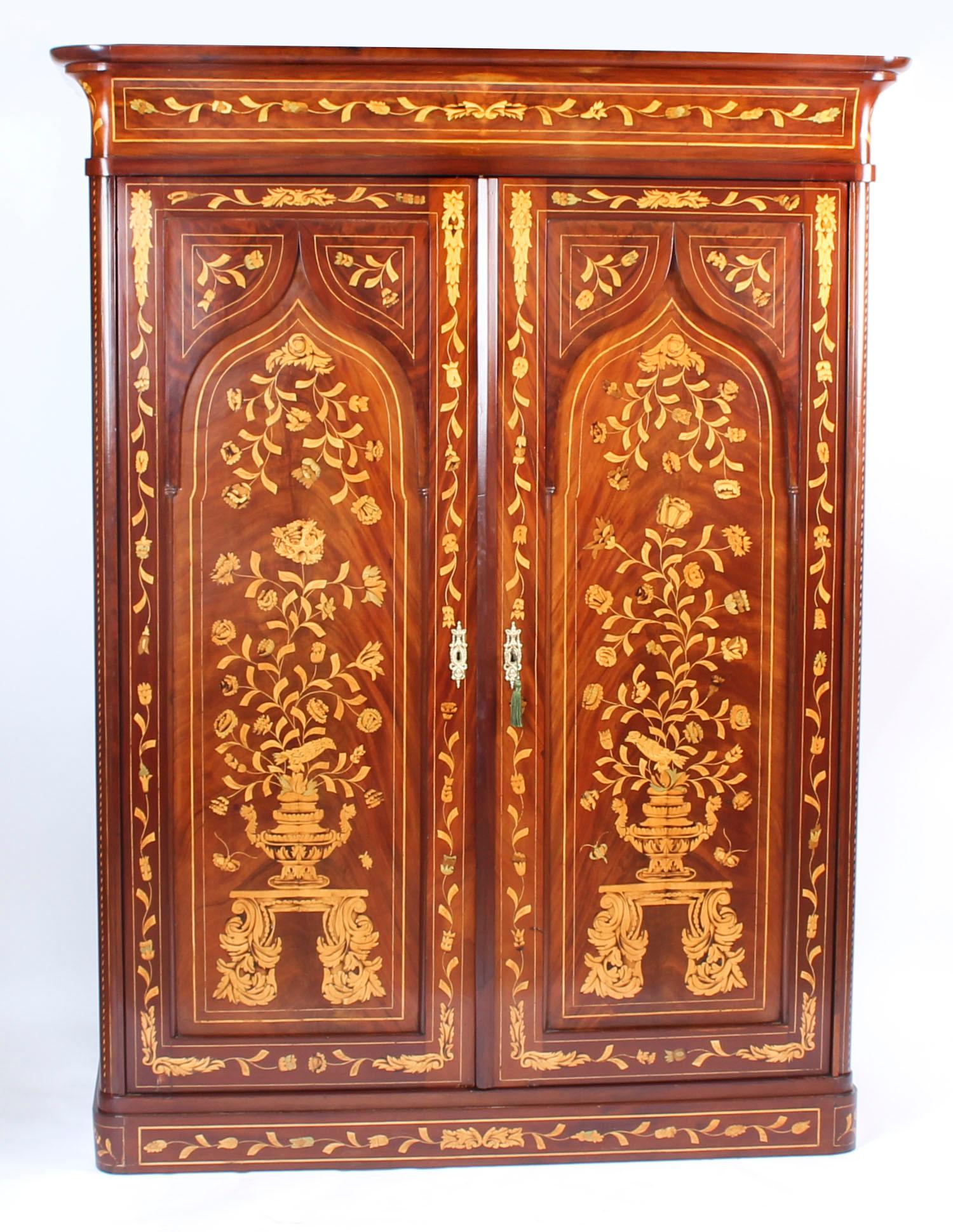 A 19th century Dutch mahogany and marquetry wardrobe, moulded concave cornice above a pair of panelled doors enclosing drawers, profusely inlaid with flowering stems, insects and scrolling leaves, circa 1840. Mesures:188 cm high, 127 cm wide.
 
This