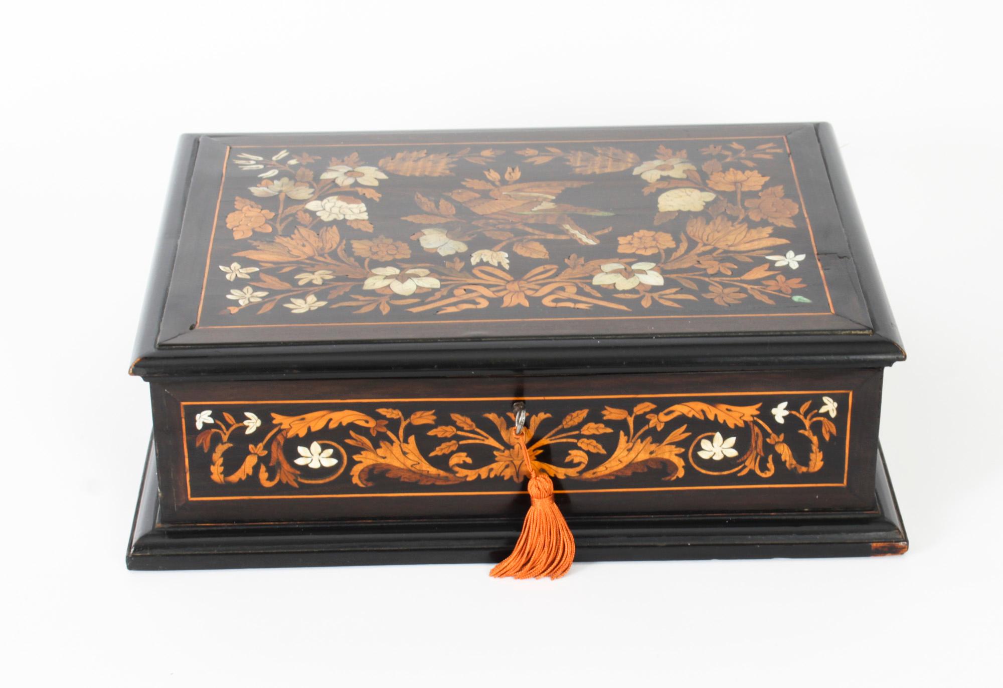 This is a beautiful antique Dutch marquetry inlaid jewellery casket, C1870 in date.

The rectangular ebonized casket has a hinged top and sides which is decorated with floral garlands, wreaths and a song bird, it opens to reveal a light blue silk