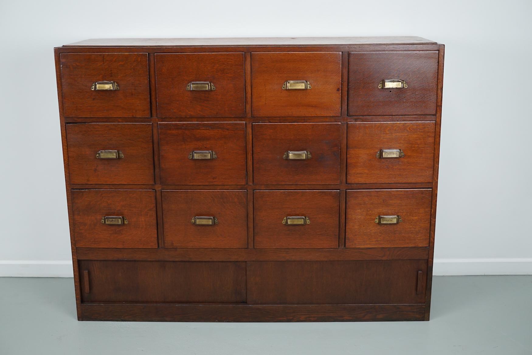 This apothecary / filing cabinet was produced during the 1930s in the Netherlands. This piece features 12 drawers and two sliding doors. The interior dimensions of the drawers are: DWH 34 x 27 x 14 / 18 cm