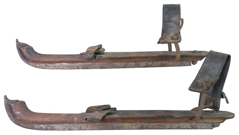 Antique Dutch ice skates featuring a steel blade with pointed tip, wood body and leather straps. Measure: 16