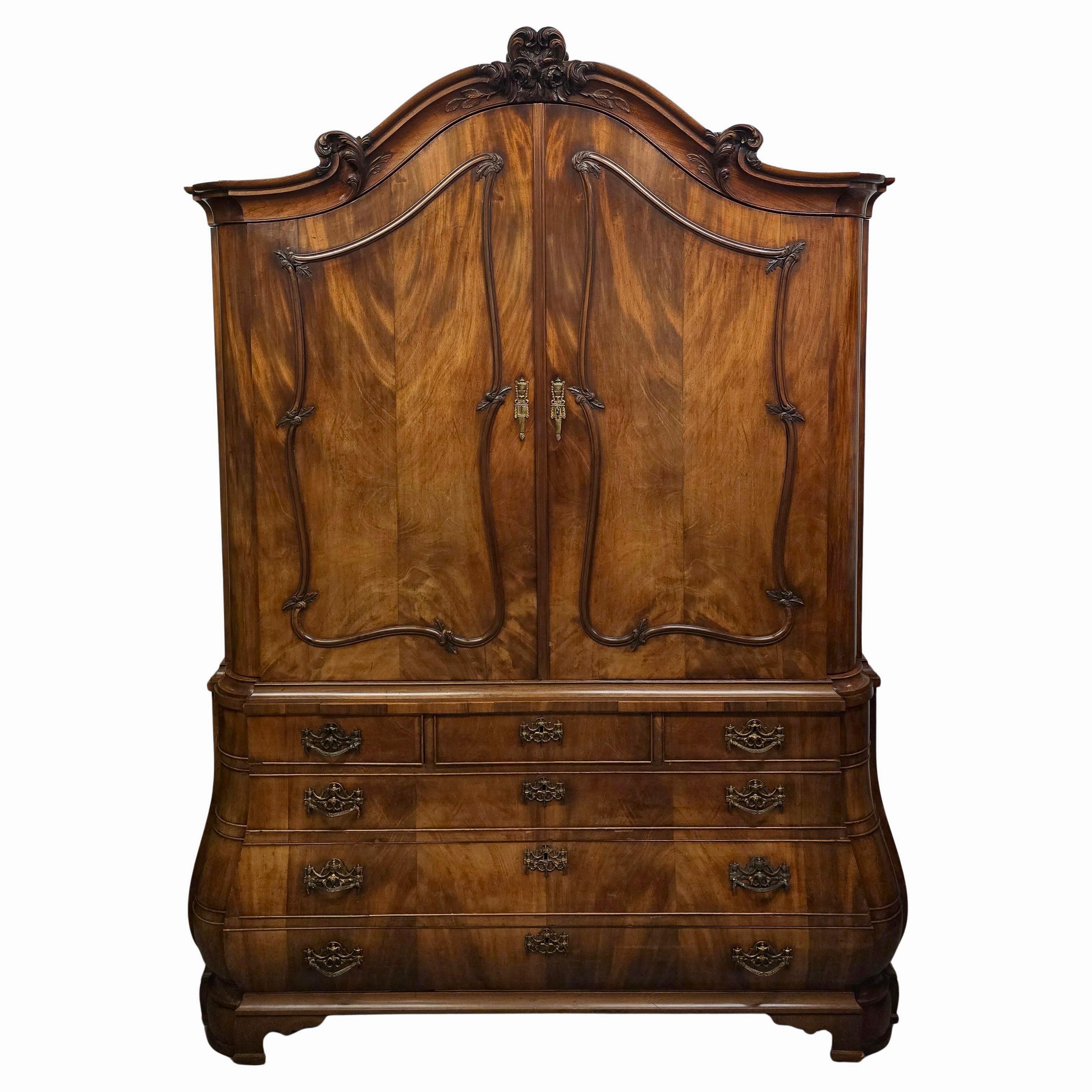 Dieser seltene und beeindruckende holländische Rokokoschrank aus der Zeit um 1750 ist ein Meisterwerk an Handwerkskunst und Eleganz. Der Schrank ist aus Eichenholz gefertigt und mit einem luxuriösen Mahagonifurnier versehen, das dem Möbelstück einen