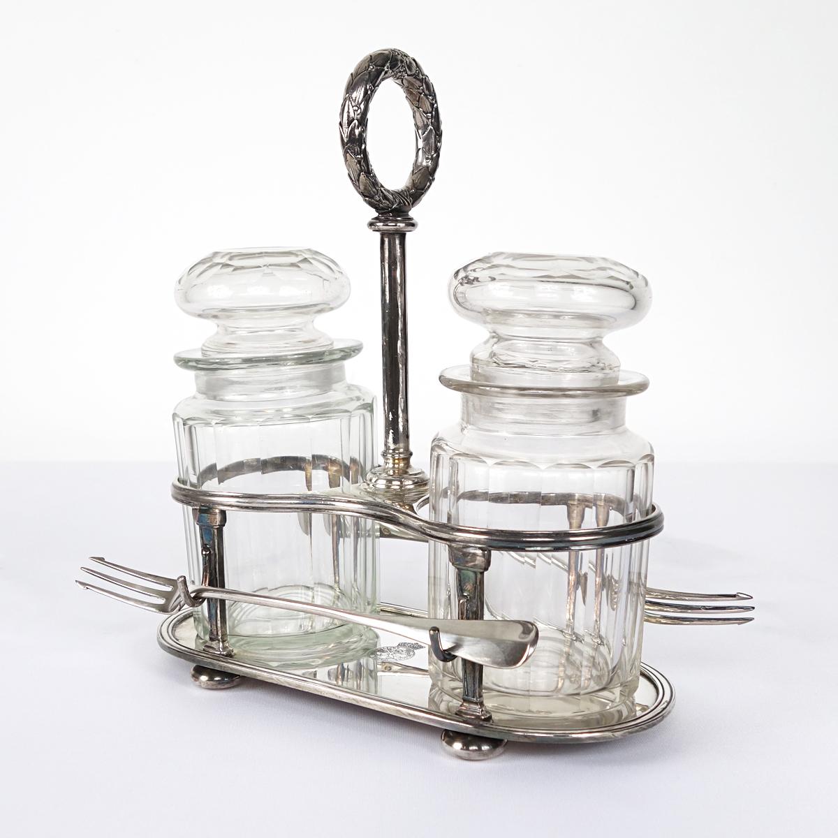 This pickle set consists of two glass jars, two small silver plate forks and a silver plate holder. It is signed 