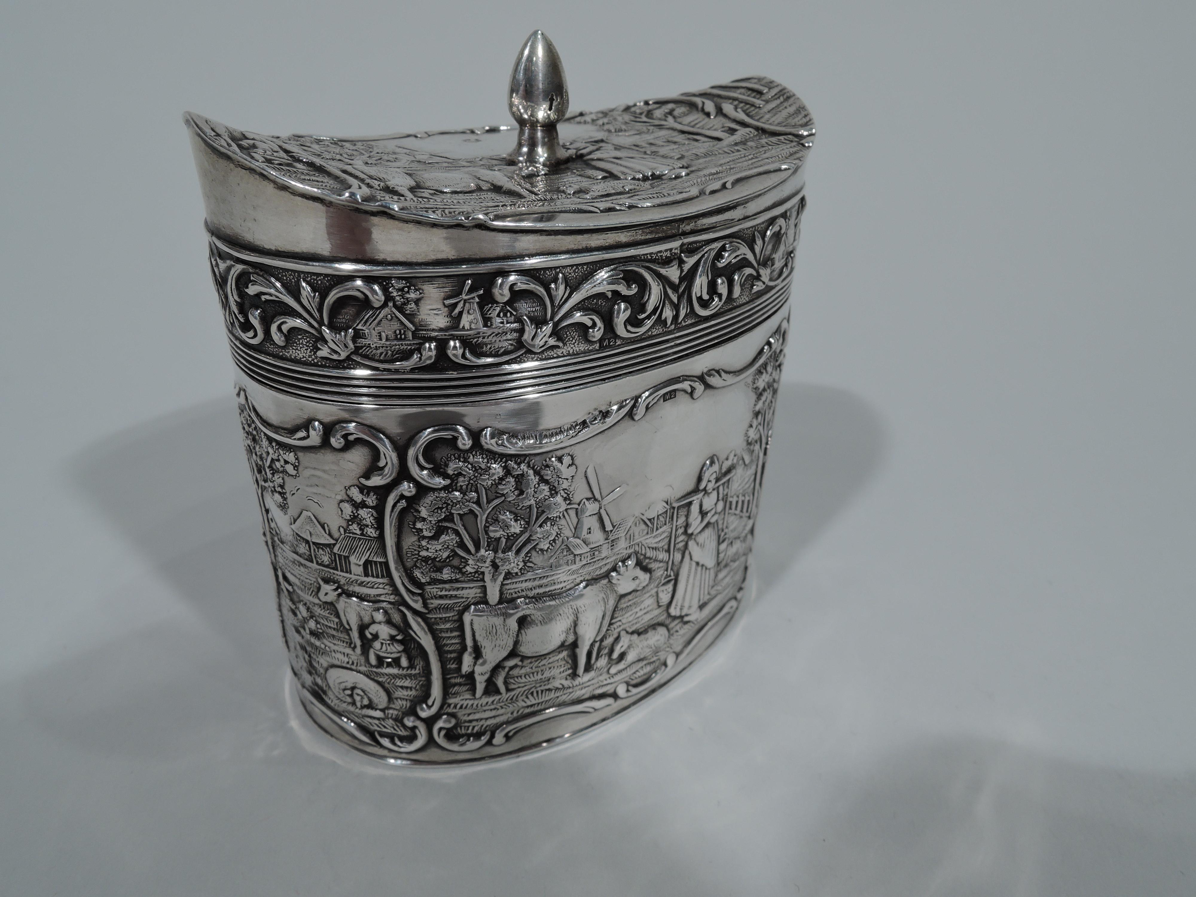 Sweet pastoral 833 silver tea caddy. Made by H. Hooykaas-Schoonhoven Silber Fabrik in Netherlands in 1927. Oval with hinged and concave cover. Chased and engraved scenes of country life in scrolled frames: Milkmaids and cows against a background of