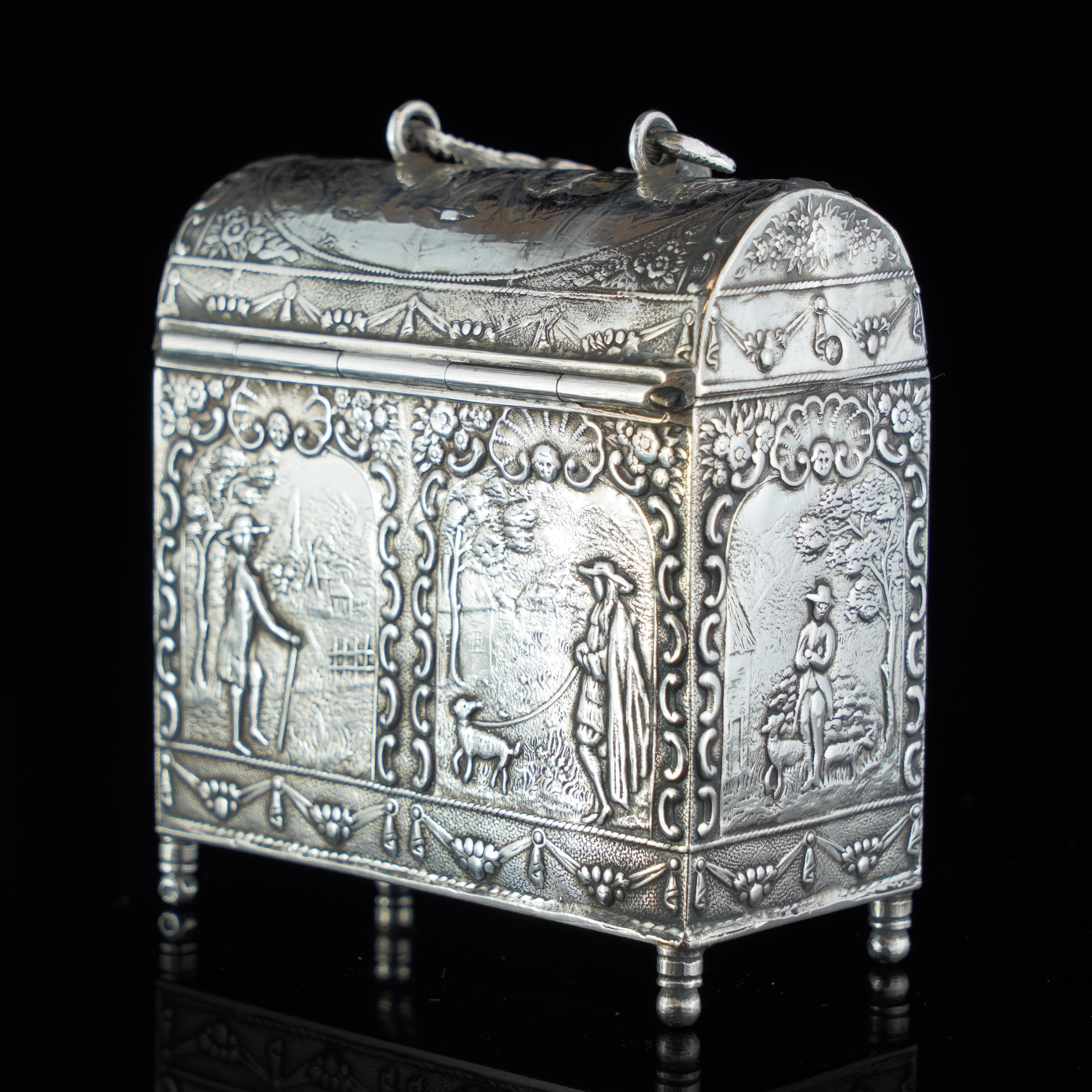 Antique Dutch silver tea caddy in the shape of a chest box, decorated with repoussé figural scene.

The surface of this tea caddy is embellished with embossed panels depicting figures at leisure in rural settings.
The surface of the concaved