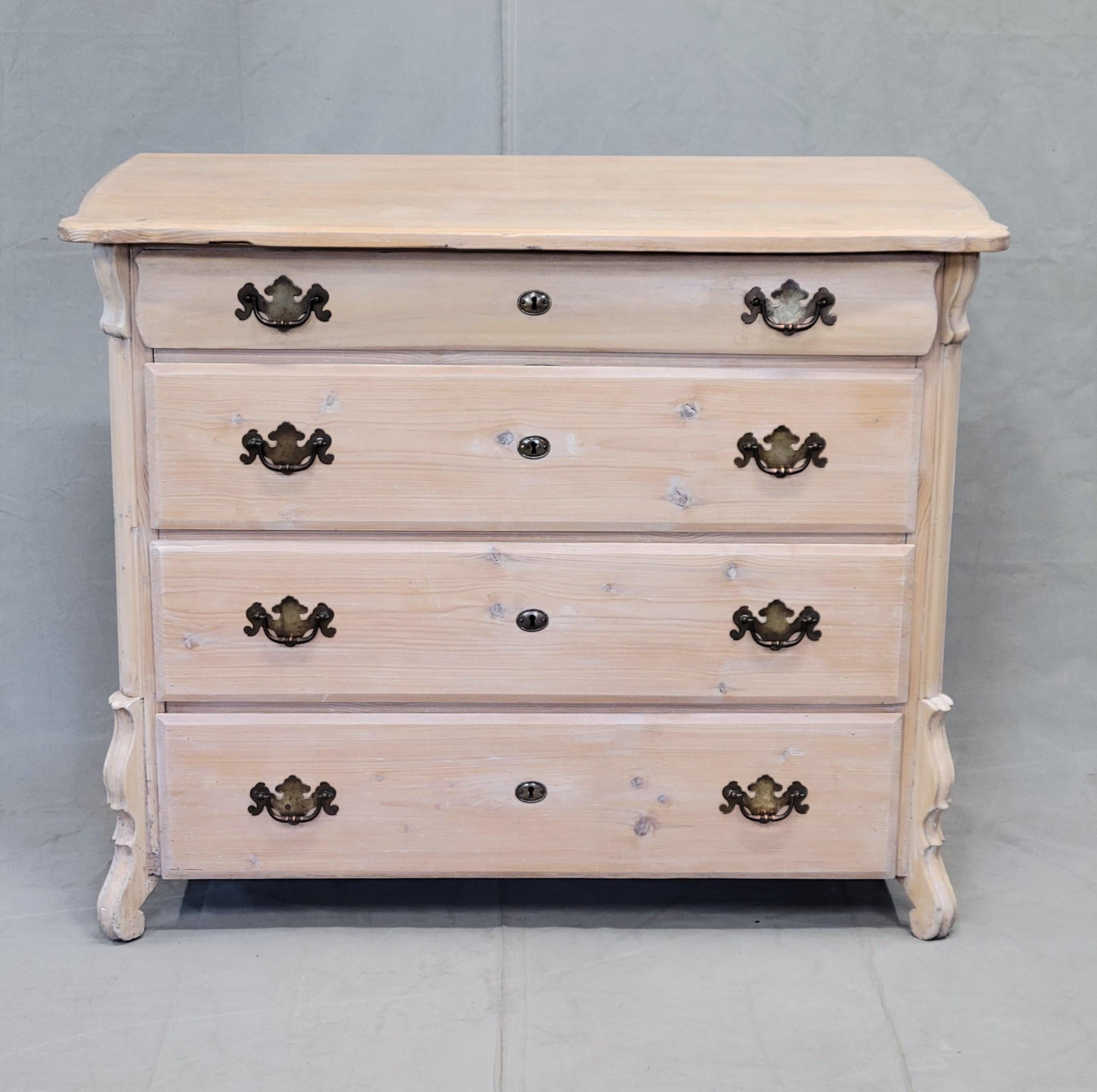 Ancienne commode en pin hollandais du début des années 1900 avec une finition cirée à la chaux blanche. Les pieds sculptés en forme d'équerre ajoutent un accent décoratif. Le profil incurvé du tiroir supérieur et du plateau de la commode ajoute au