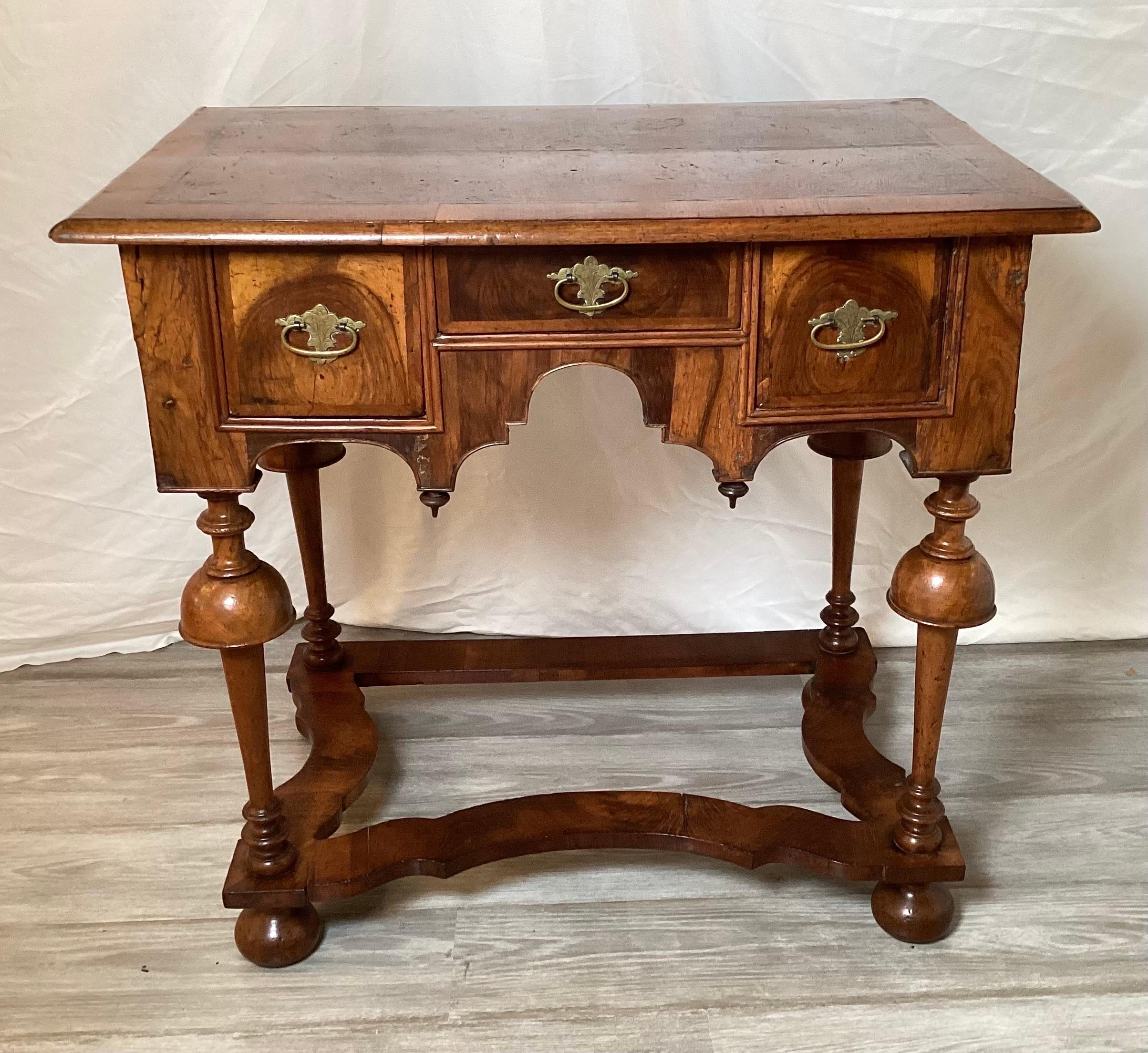 A rare and original 1715 William and Mary burl walnut lowboy. The three drawer case resting on hand turned trumpet form legs. Original hardware.