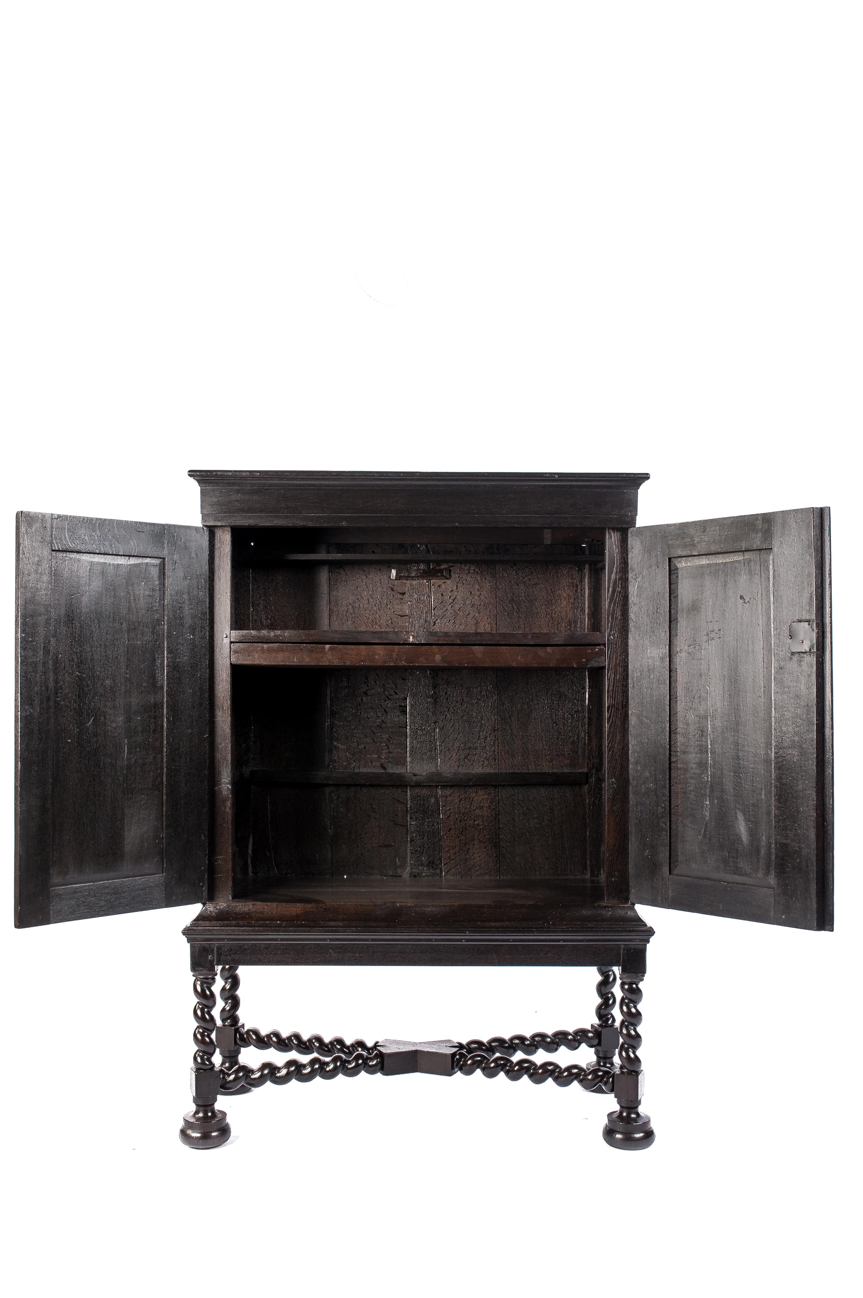 A beautiful handcrafted two-door cabinet that was made in The Netherlands at the end of the Dutch golden age. The piece consists of two pieces, an impressive barley twist base with a cross stretcher with a two-door cabinet on top. The cabinet was
