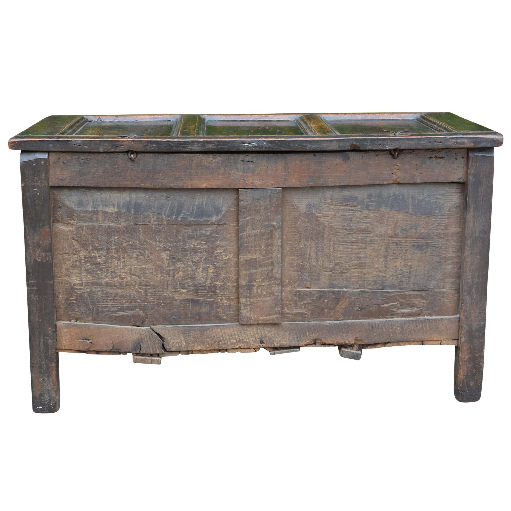 An antique English carved oak three-panel chest has beautiful patina from the centuries of use. The façade has a detailed carved, scrolled-foliate frieze with the initials “GS” on the lock plate cutout as well as diamond motifs on the lower three