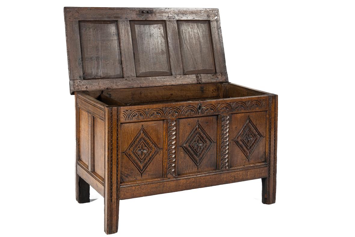 This fine oak chest was crafted in England around 1700 and stands as a beautiful example of the solid yet stylish furniture of the period. The front is richly decorated with geometric panels featuring carved diamond shapes with floral motifs,