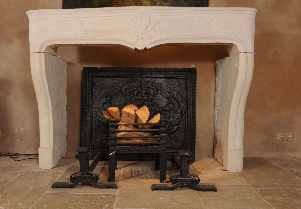 An elegant antique limestone fireplace from the early 18th century French Baroque with a beautiful decoration of a French lilly. The measurements of this mantelpiece are H 144 x W 155 x D 69 cm, opening sizes are H 90 x W 130 cm.