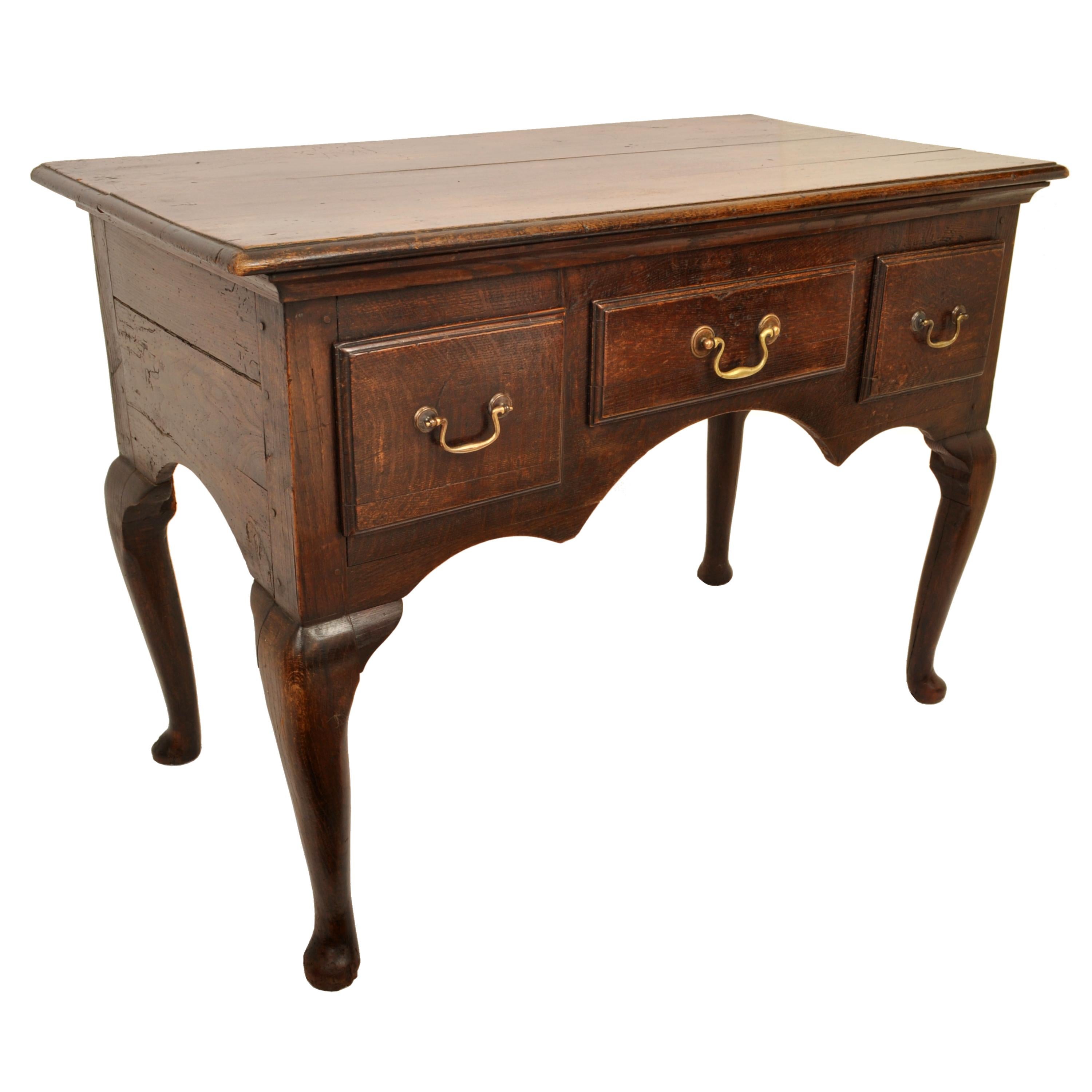 A good and early antique Georgian oak lowboy/dressing table, circa 1750.
The George II lowboy having an overhanging top, with a carved kneehole with three drawers above, each having brass bail handles. The lowboy is raised on cabriole legs