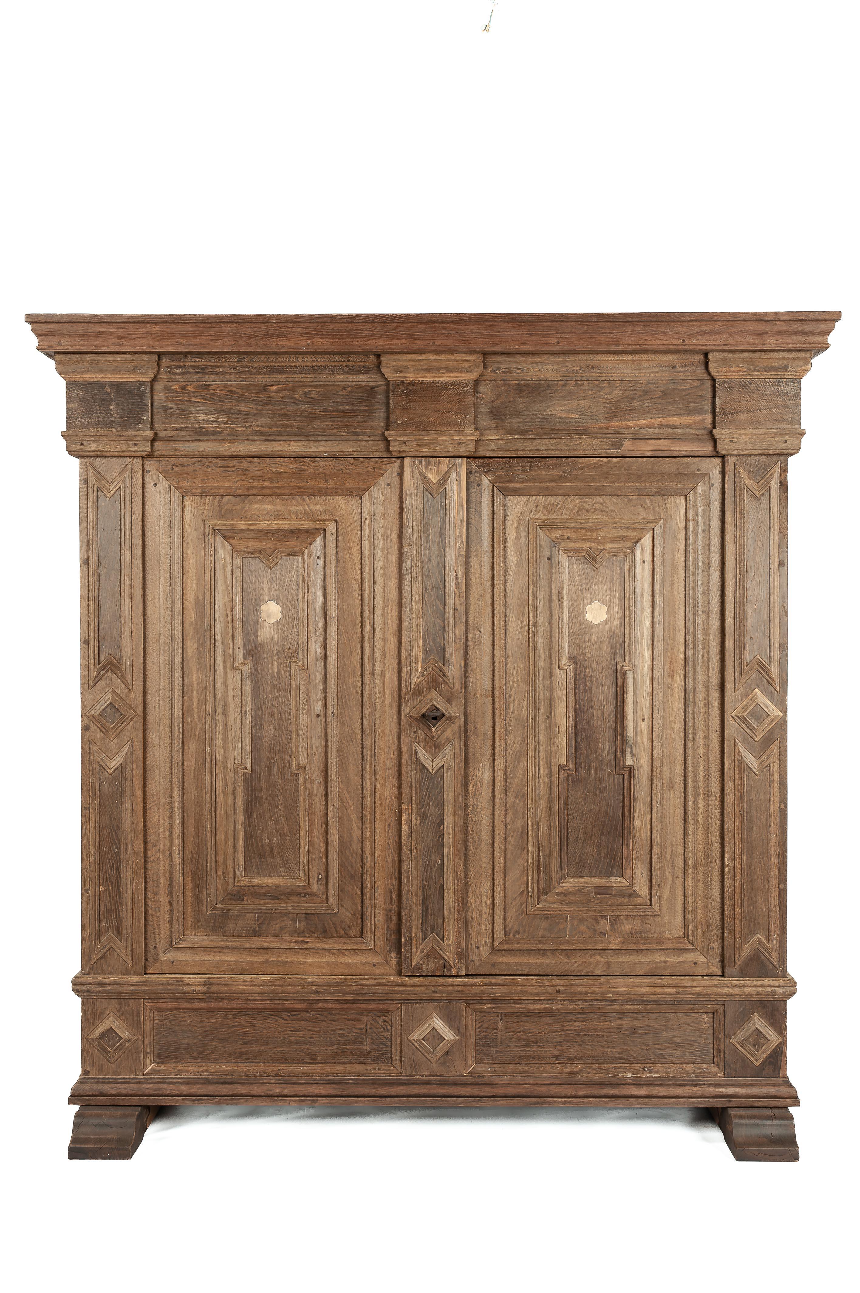 This antique oak cabinet was crafted in the early 20th century in the German state of North Rhine-Westphalia around 1720. The cabinet was entirely built from the finest quality European summer oak. It features two doors and is richly adorned with