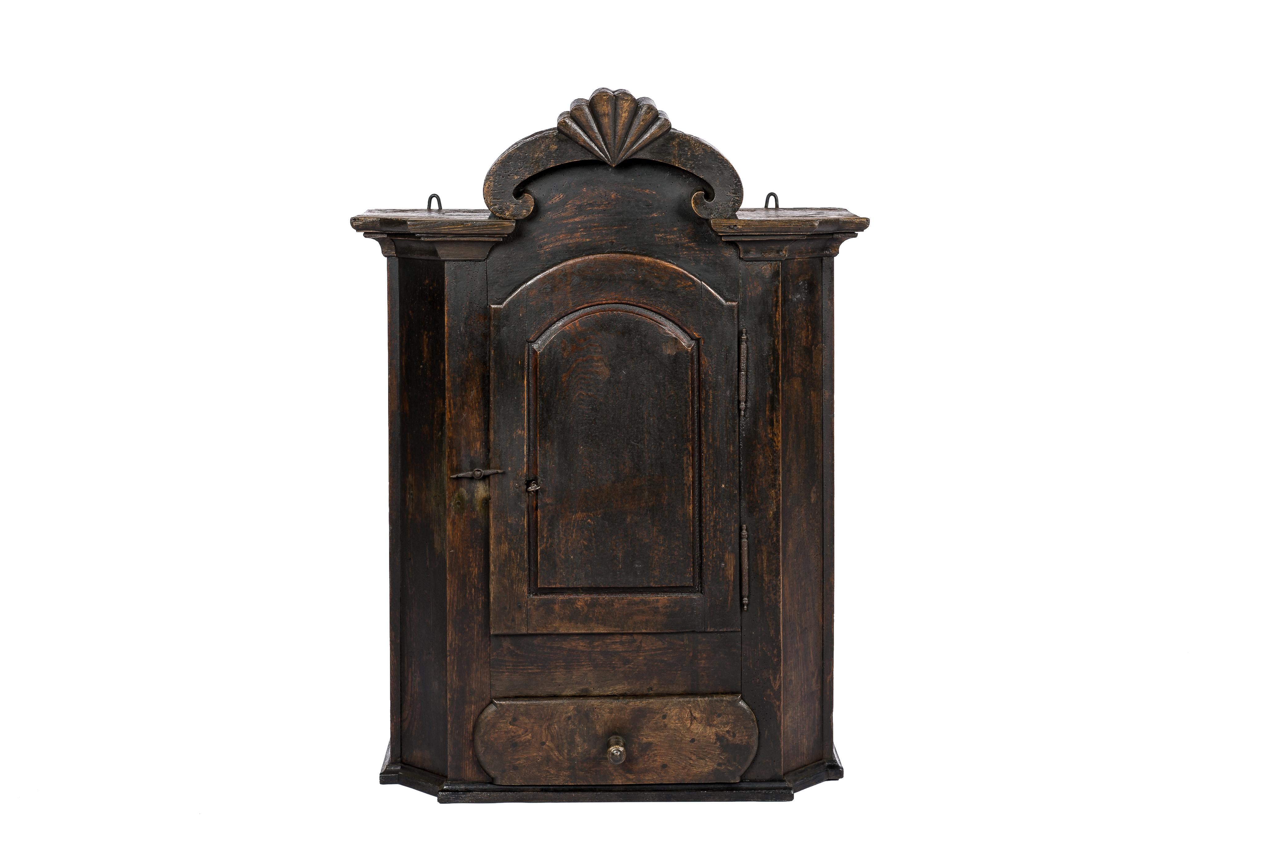 This very rare and exceptional antique baroque hanging cupboard was made in central Germany in the early 18th century circa 1720. It was made from solid oak and pine and was painted in a very dark brown color. This elegant cupboard features slanted