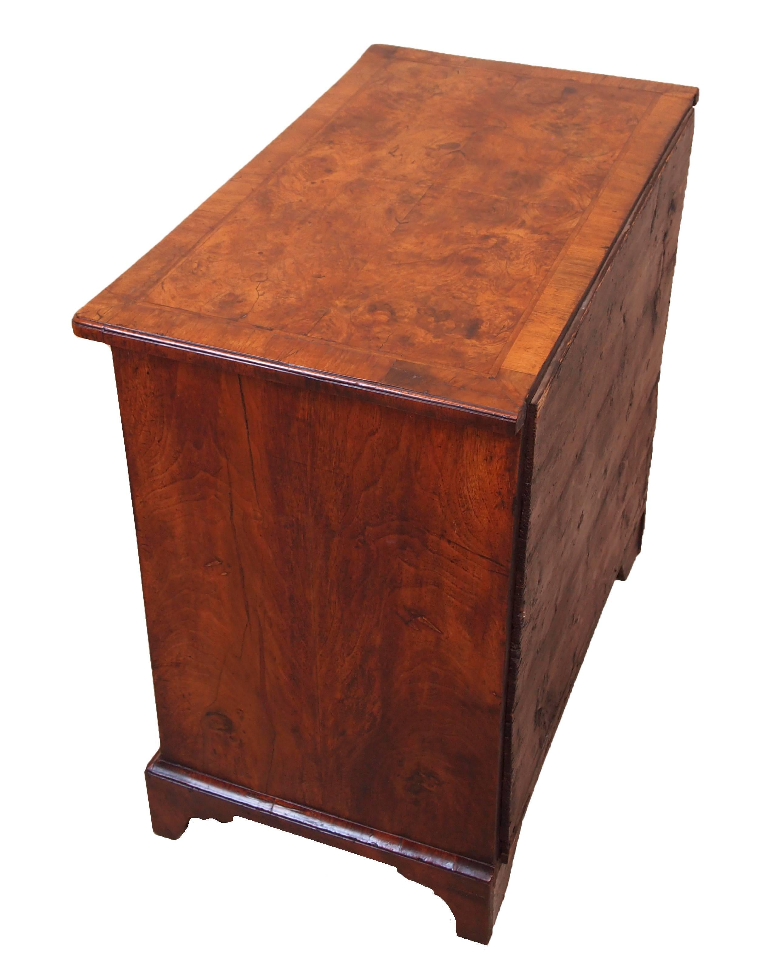 A delightful George I period burr walnut kneehole
desk of diminutive proportion having superbly figured
and crossbanded quarter veneered top above drawers
with replaced brass handles surrounding central
cCupboard door raised on original shaped