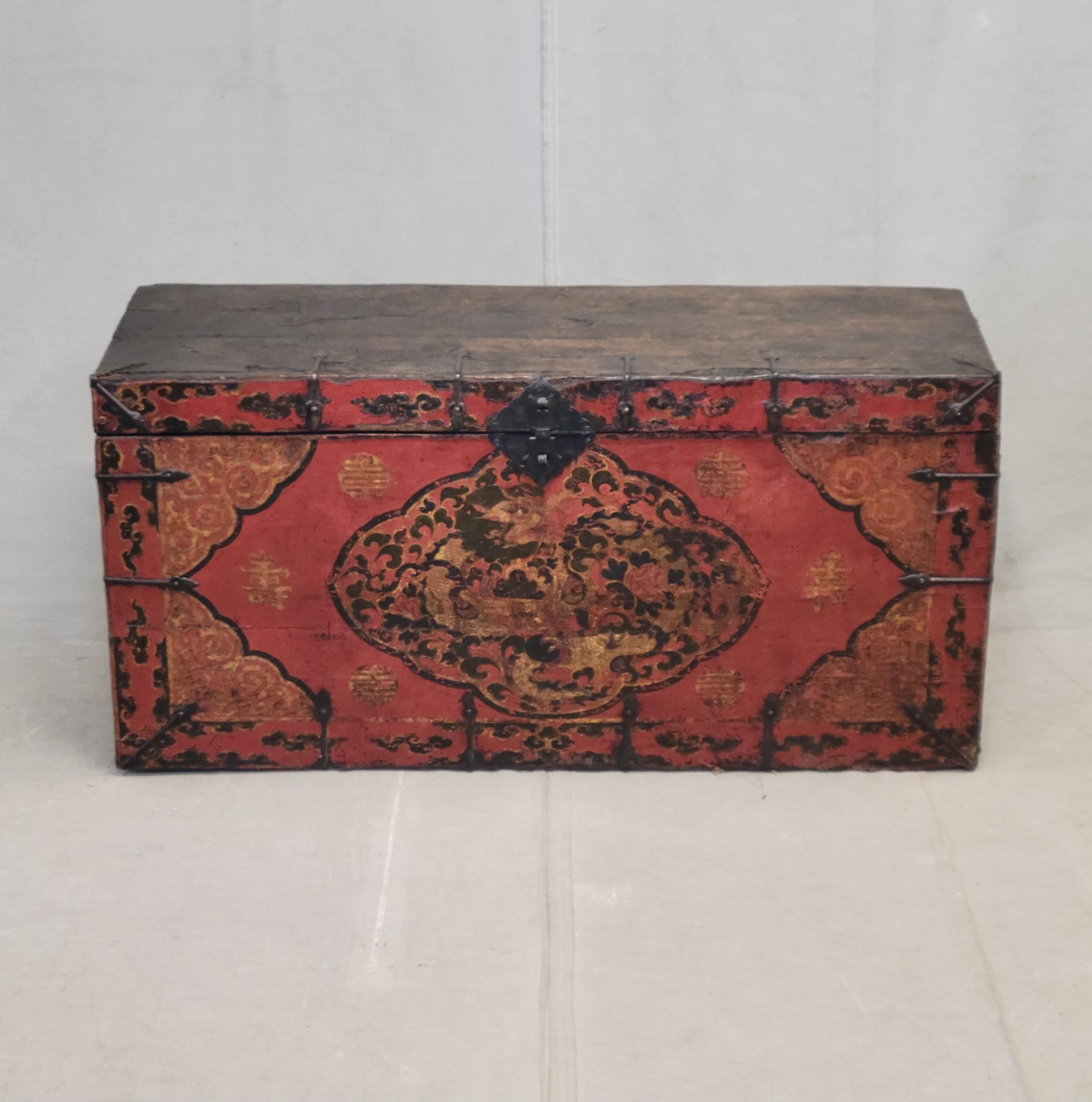 A beautiful antique early 1900s lacquer storage box or trunk from Tibet. The red, green, black and ochre lacquer on the box front is used to create a stunning dragon motif as well as scrollwork, clouds and flowers. The top of and sides of the box
