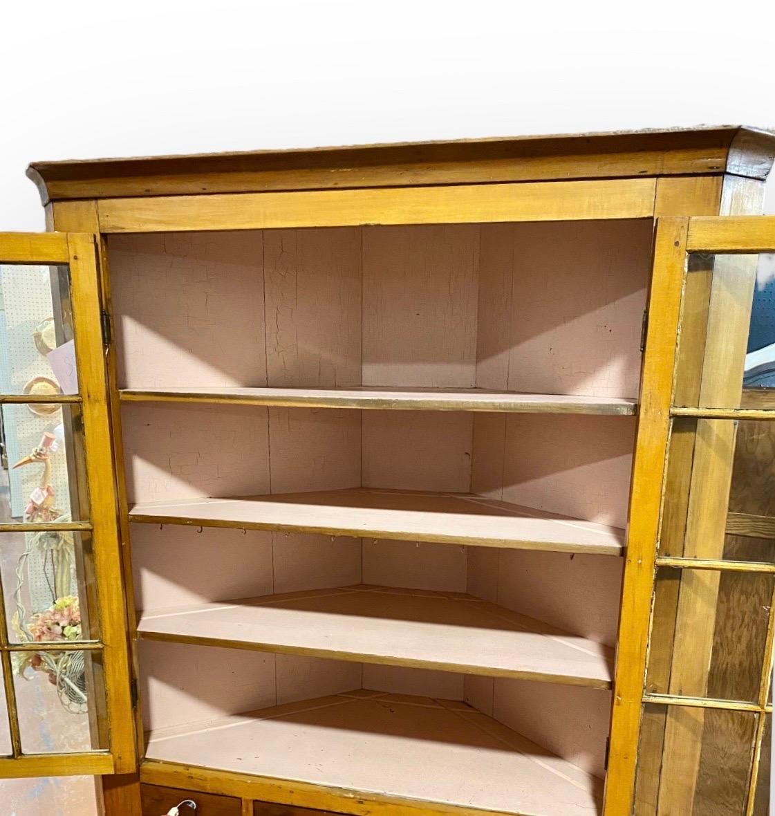 Antique early 19th century American pine and maple Corner Cupboard, c 1810. Made of pine and maple, featuring triangular form with stunning original glazed wavy glass doors, three drawers and wood doors below This cupboard has pale pink old milk