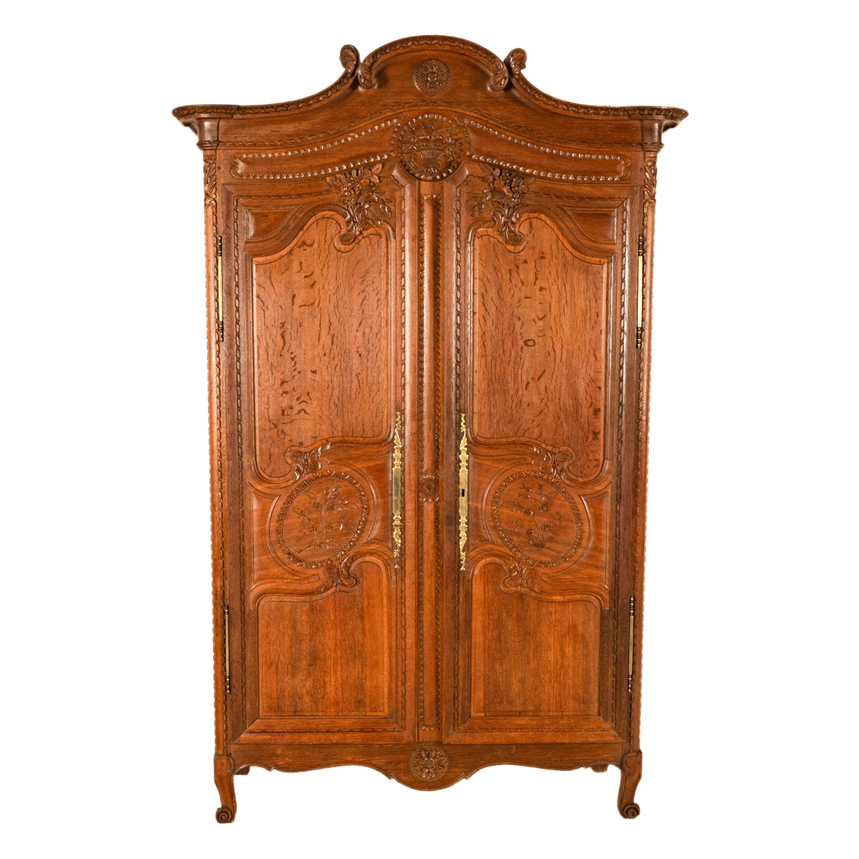 Un raffinato ed elegante armadio nuziale in quercia intagliata francese degli inizi del XIX secolo, Normandia, circa 1820.
L'armadio è finemente intagliato e presenta una cornice intagliata ad arco e a volute, sotto c'è un tondo intagliato con un