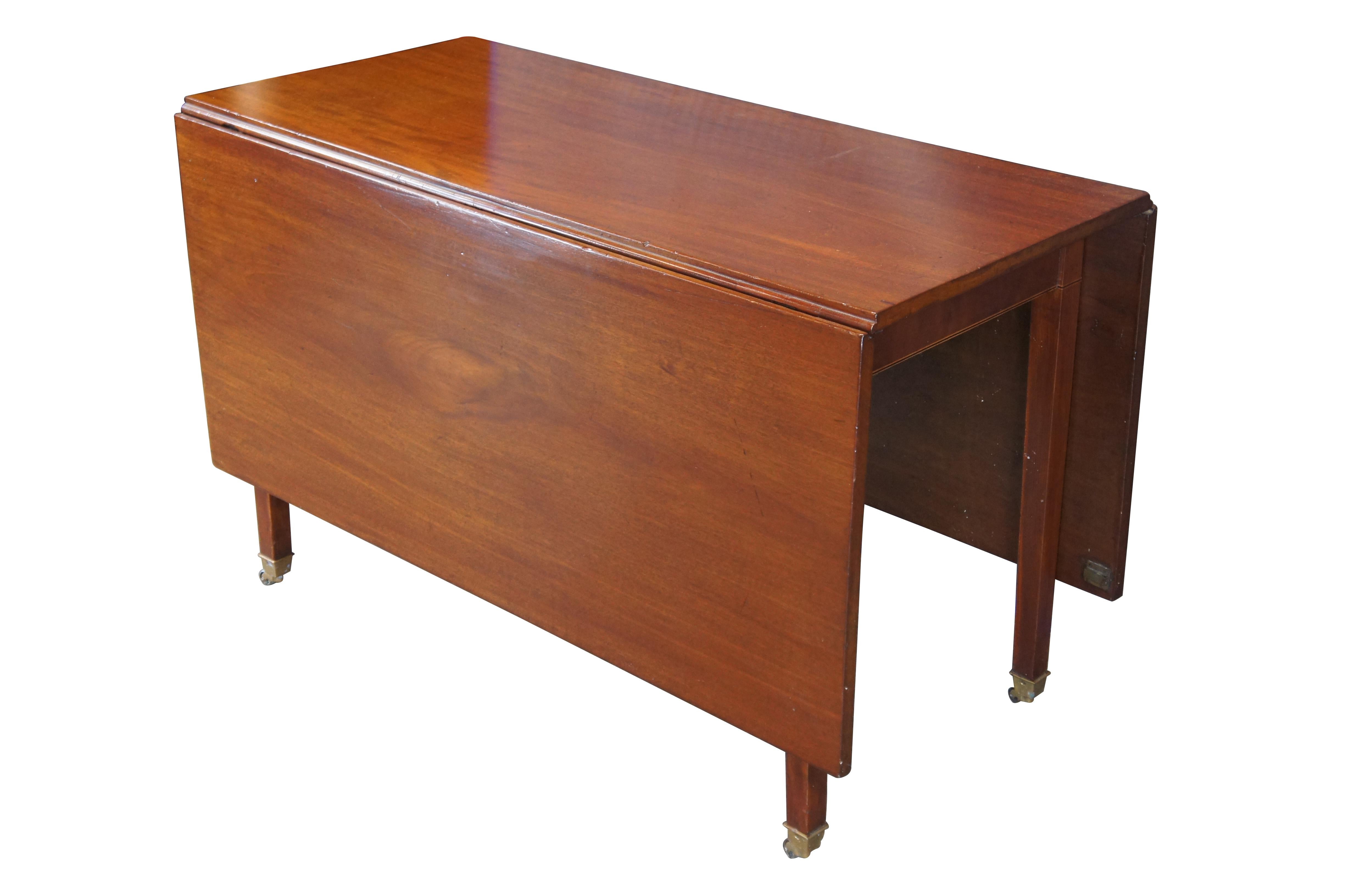 Ancienne table de salle à manger en acajou, de style Feder / Georgian, de forme rectangulaire avec deux grandes feuilles, des pieds de porte et des roulettes en laiton.  Circa début du 19ème siècle.

Dimensions :
22