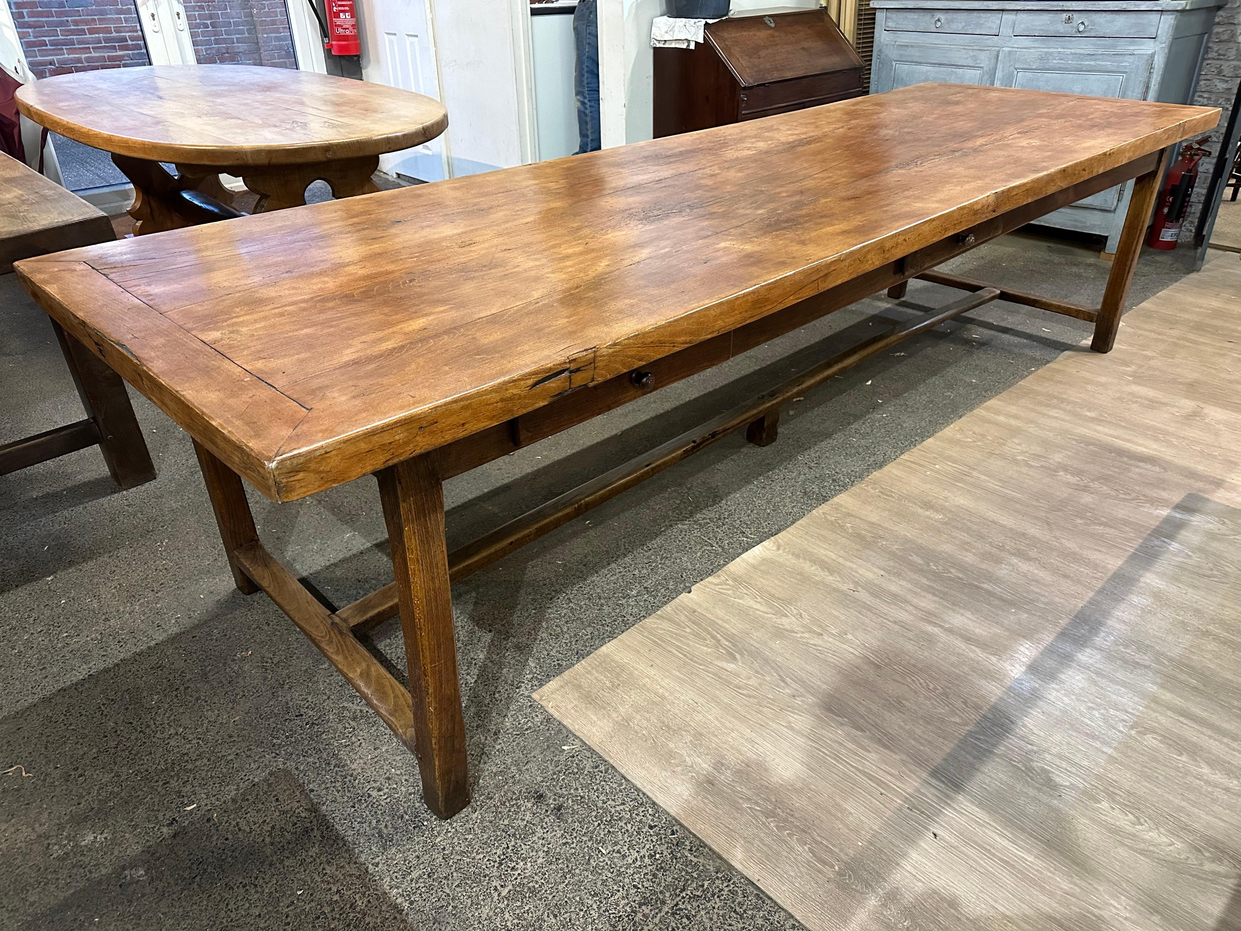 This exquisite early 19th-century farmhouse table is a true statement piece. Crafted from solid beech wood, it boasts a substantial size, measuring 3 meters in length and 1 meter in width. The table's rich honey colour exudes any space. The table