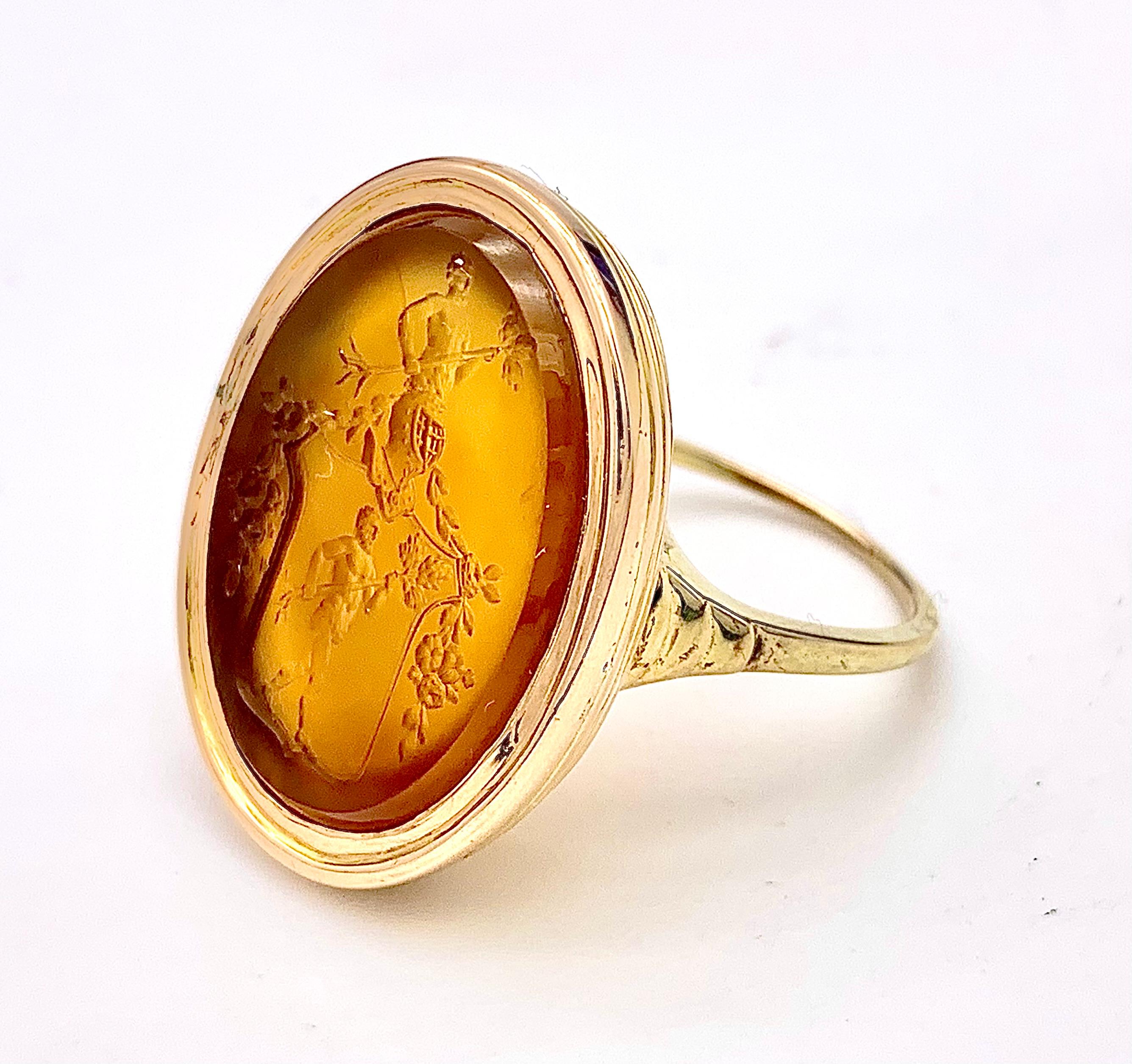 The oval carnelian intaglio shows a heraldic crest. Depicted is the outline of a shield with a helmet. Inside the shield a striding man with a beard dressed only with a loin cloth is holding a young tree with its roots in both hands. Out of the