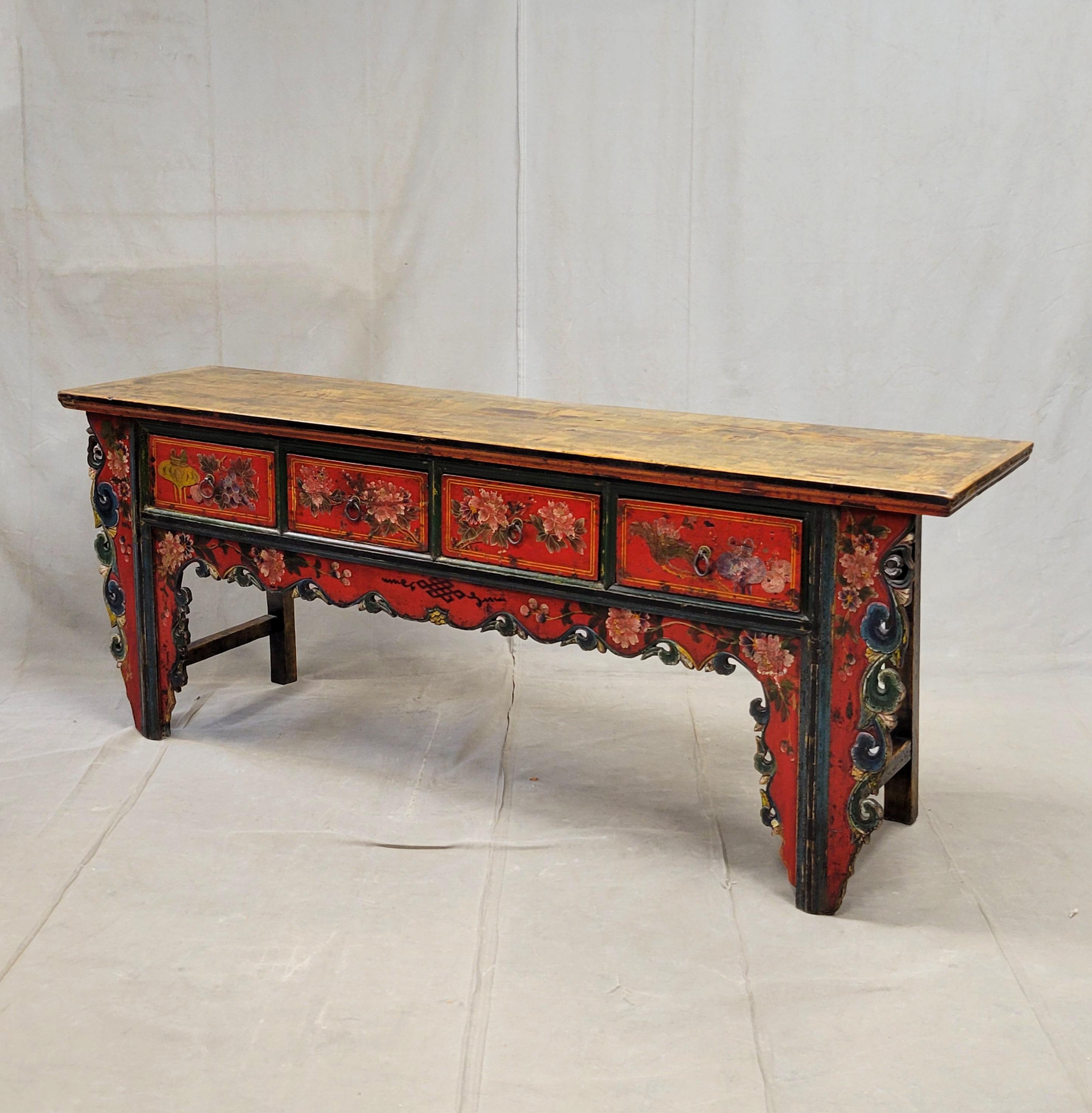 An exceptional early 20th century four drawer altar or console table from China. The front is embellished with incised and pierced carving and lacquer in shades of red, black blue and white. Imagery of flowers, grapes and cloud formations along the