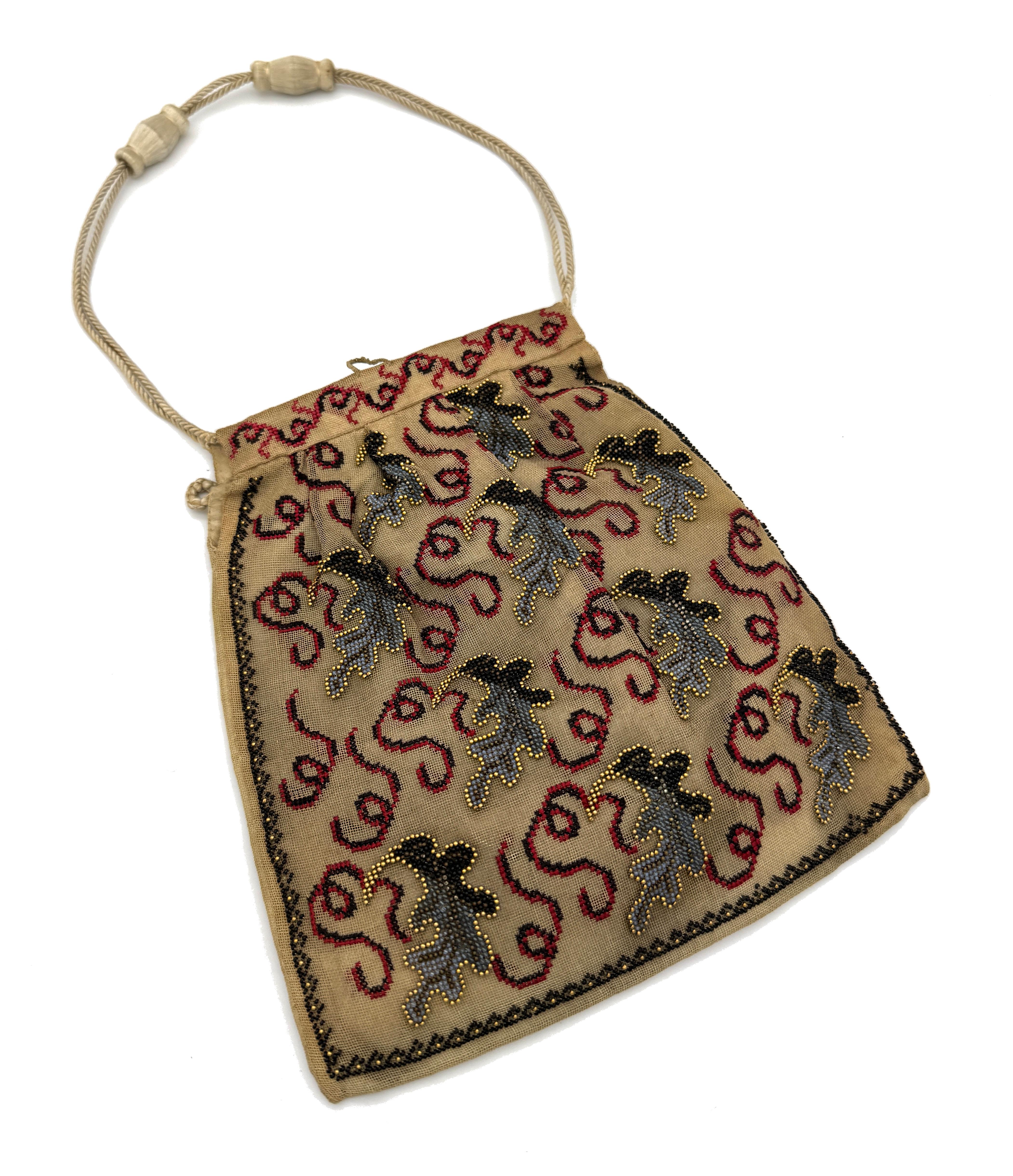 This rare and delicate bag was handcrafted in the early 19th century. The silk is covered with a net that is used for embroidering. The handbag is decorated on one side with hand embroidered flowers in red, yellow, light and dark green. The flowers