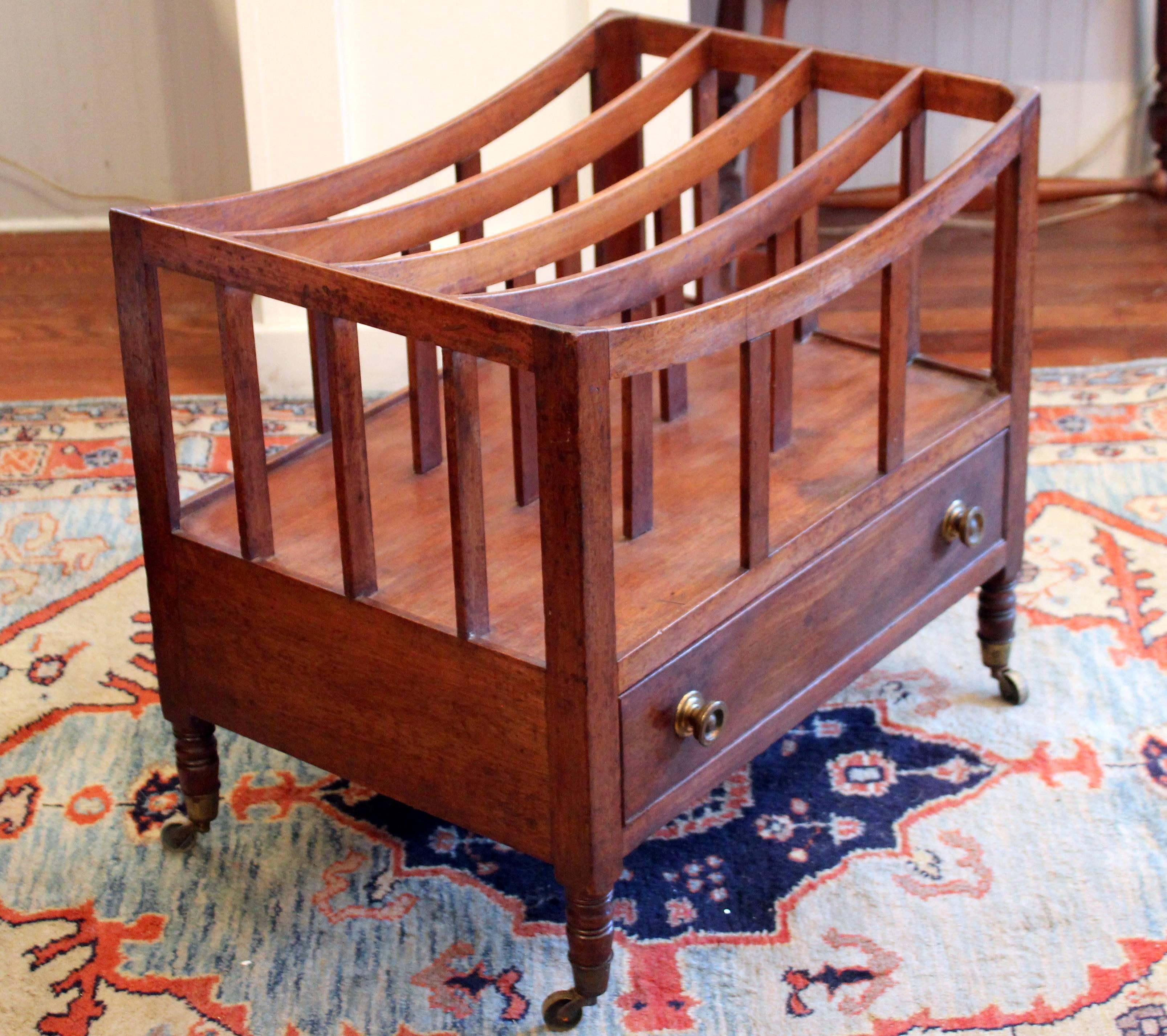 Antique English Regency mahogany canterbury with four slatted divisions over a single beaded drawer and raised on slender turned legs and brass castors, circa 1820. Several undercarriage supports and a drawer runner replaced, as shown.