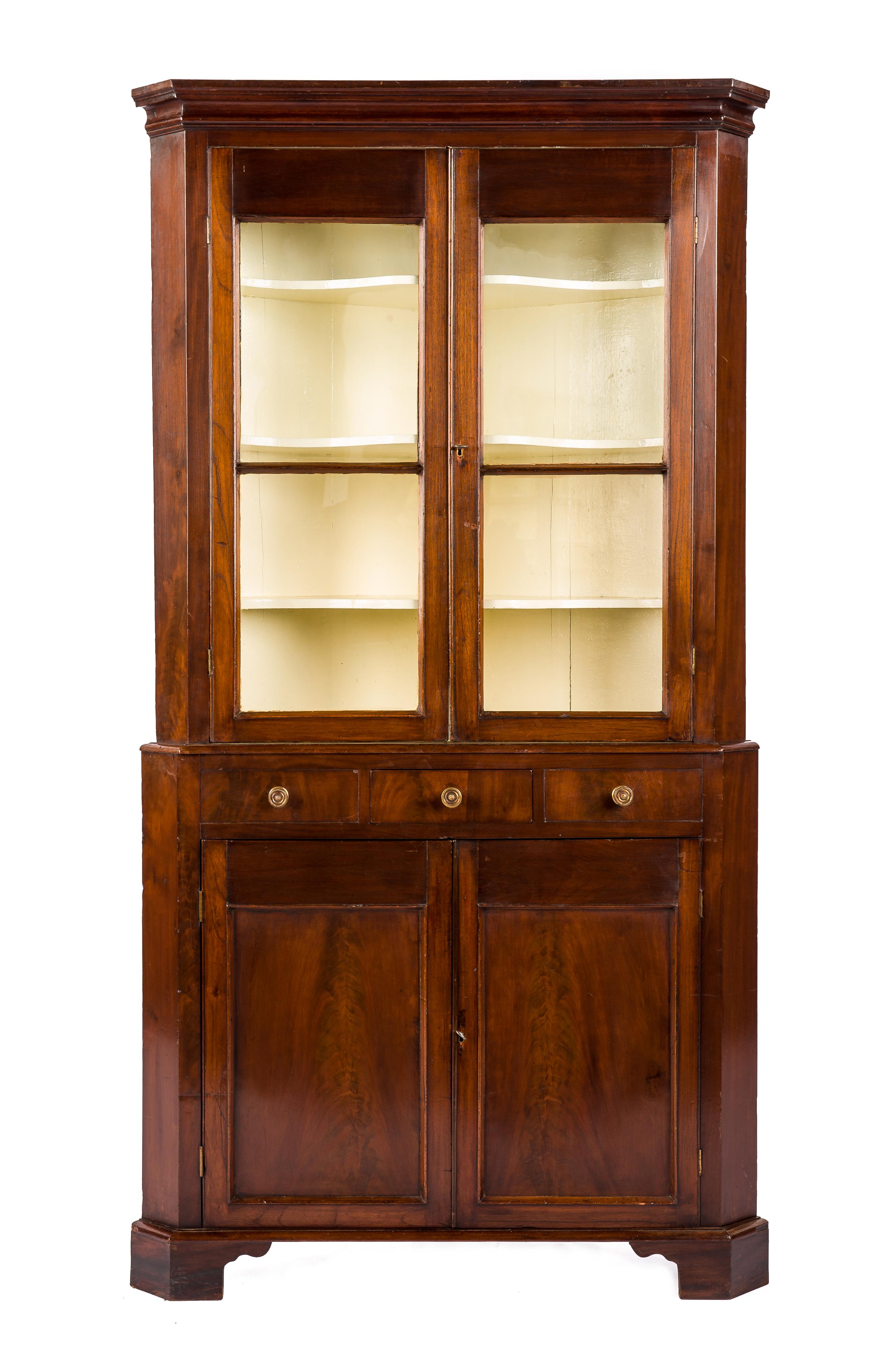 This beautiful antique glazed corner cupboard was made in the United Kingdom in the early 19th century circa 1820. The cupboard breaks down into a lower and an upper cabinet. The lower cabinet is 37 inches high and features three drawers over two