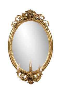 Antique early 19th century French Rococo gold oval mirror with candle holders