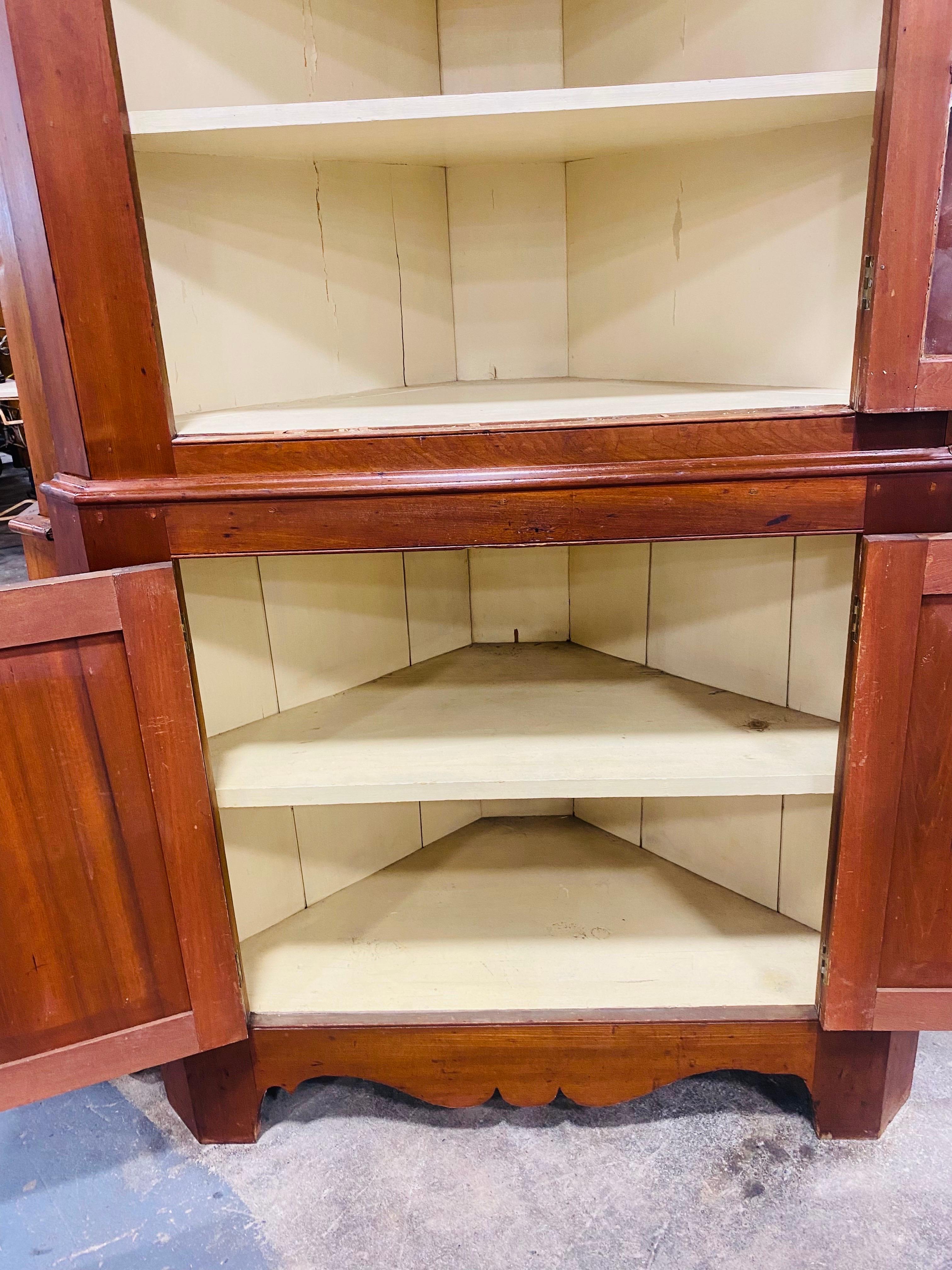 Il s'agit d'une armoire d'angle en merisier antique fabriquée à la main au milieu du 19e siècle. Cette antiquité américaine classique comporte des panneaux en verre soufflé à la main sur les portes avant, ainsi que des boutons en verre d'origine. Ce