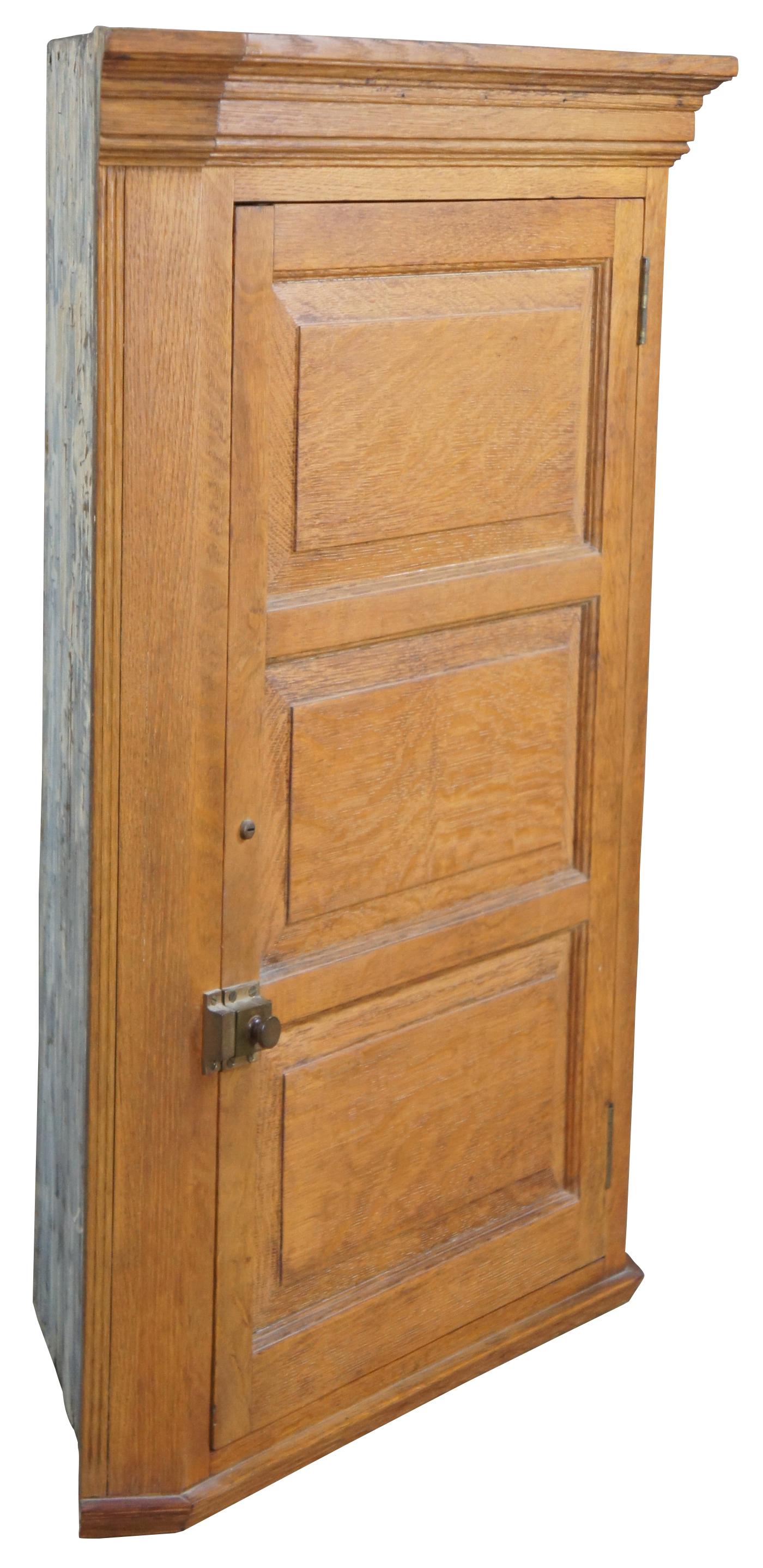 Early 20th century oak hanging corner cabinet or cupboard. Features 3 shelves behind a paneled (tiger) quarter sawn oak door with brass latch. Measure: 38”.
   
Graduated from corner - 20.25