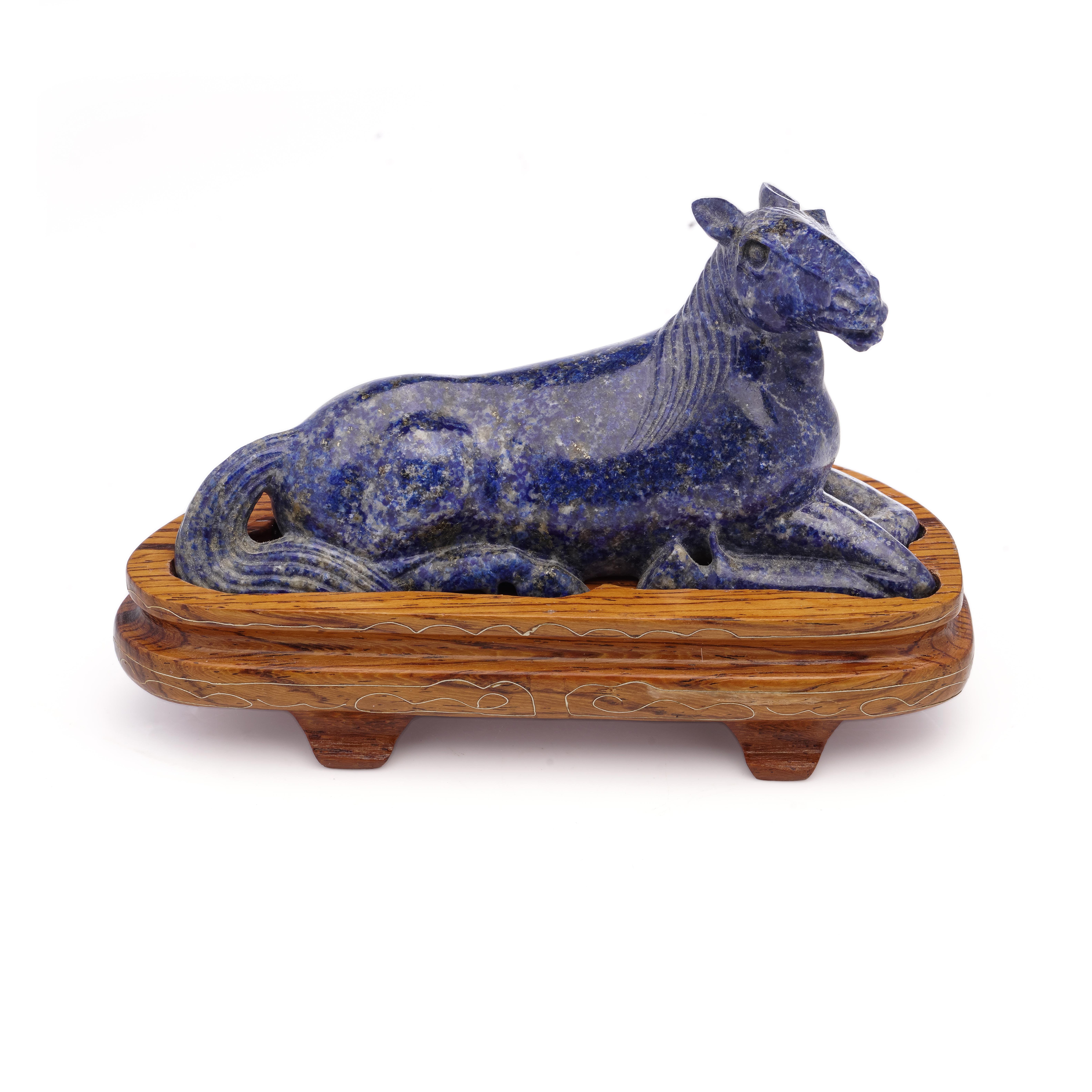 Antique early 20th century Chinese carved lapis lazuli figurine, featuring a recumbent pose with a wood base stand. 

The dimensions: 
Horse size: Approximately 11 cm in length and 3.5 cm in width and 5.5 cm in height. 

Wood base length x