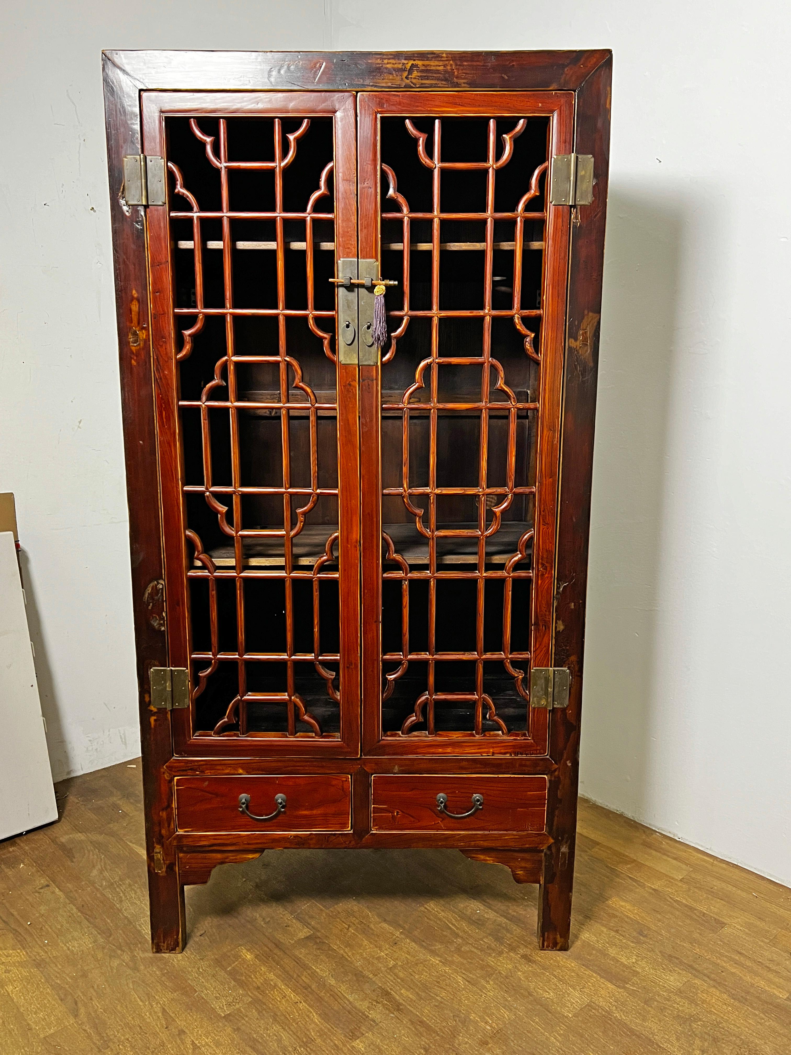 An early 20th century Chinese open fretwork pantry cabinet in rich amber lacquer.