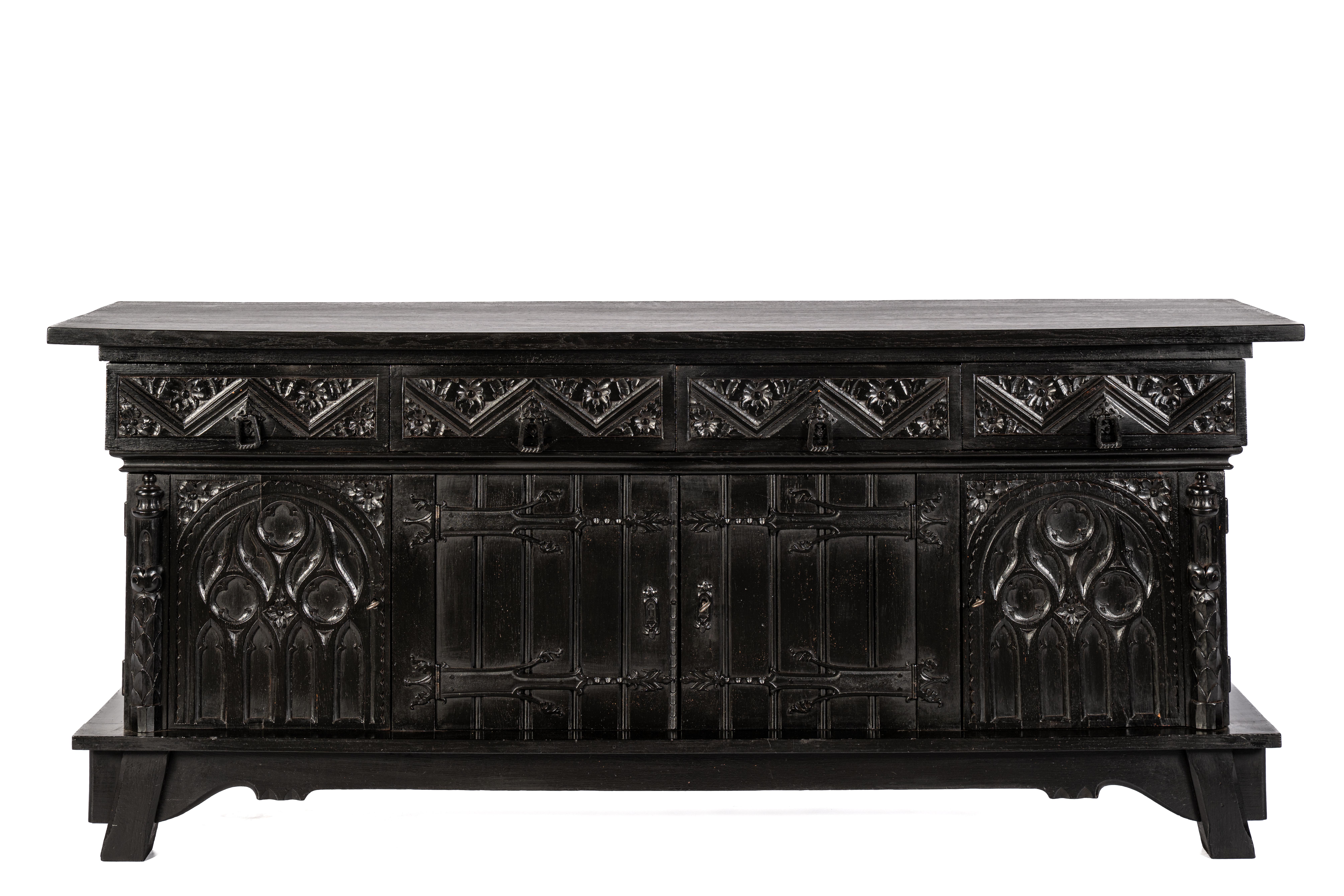 This is an impressive Neo-Gothic sideboard, crafted in the Netherlands around 1920. Made from solid oak, the piece was recently blackened, which enhances its Gothic stylistic features. The cabinet is designed with four doors and four upper drawers,