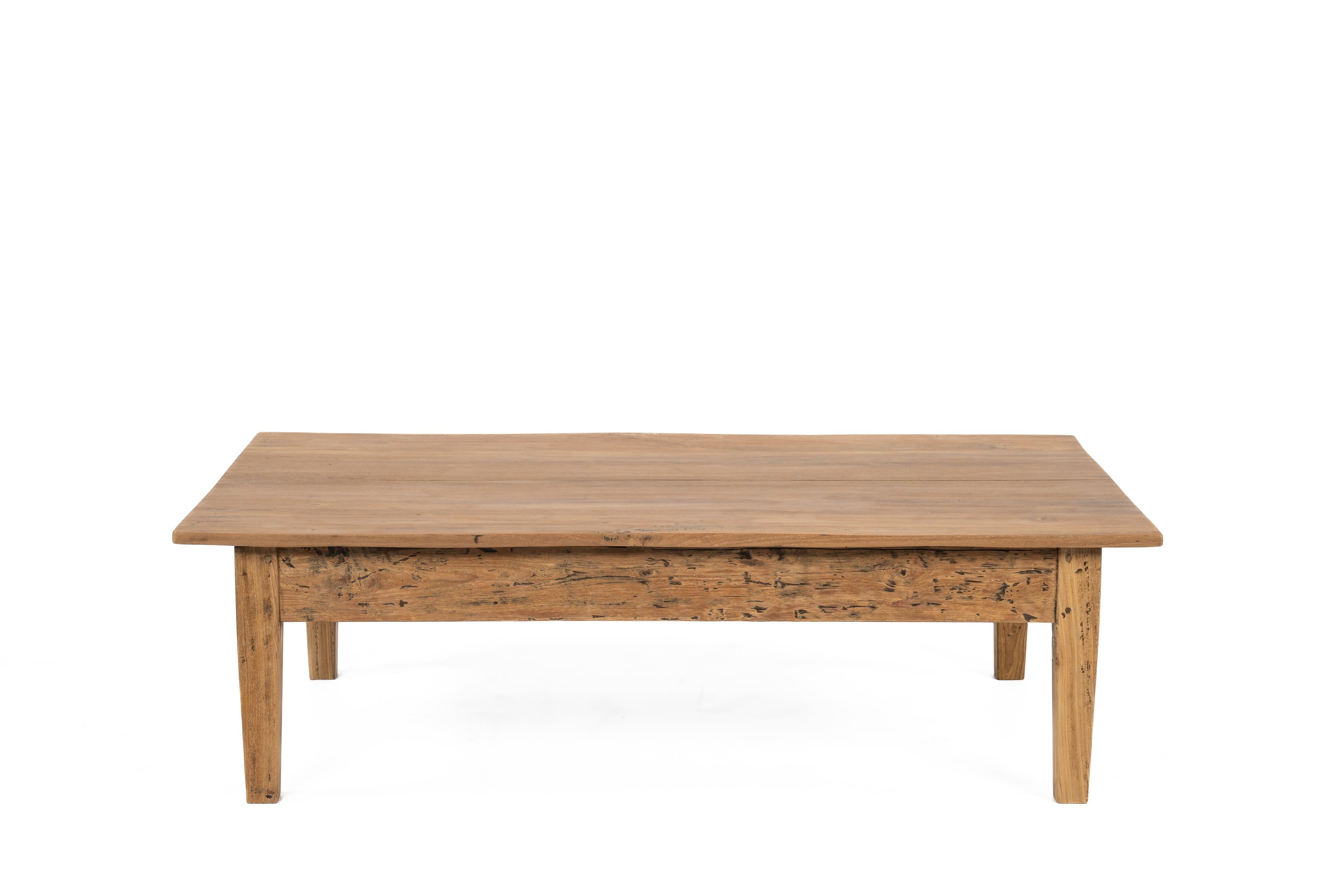 Here presented is a beautiful antique coffee table crafted from teak wood in the early 20th century, circa 1910. The table features a top made of two wide planks. Below it, there is a sleek framework connected by slightly tapered legs. This table