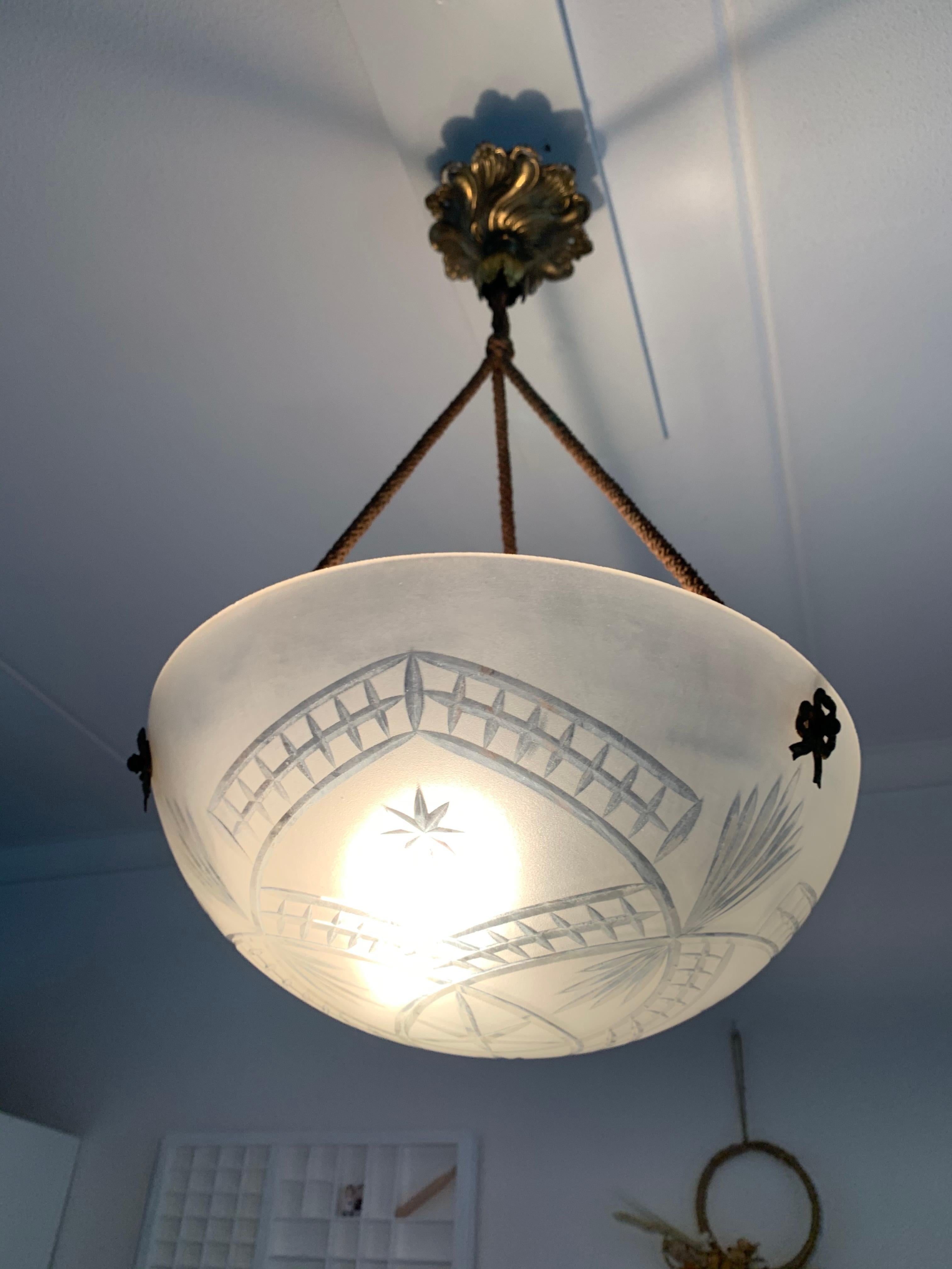 Beautiful early 1900s French fixture, still hanging from its original rope.

The wonderful design of the hand engraved motifs in the sizable glass shade make this antique light look like a cut diamond hanging from your ceiling. Both with the light