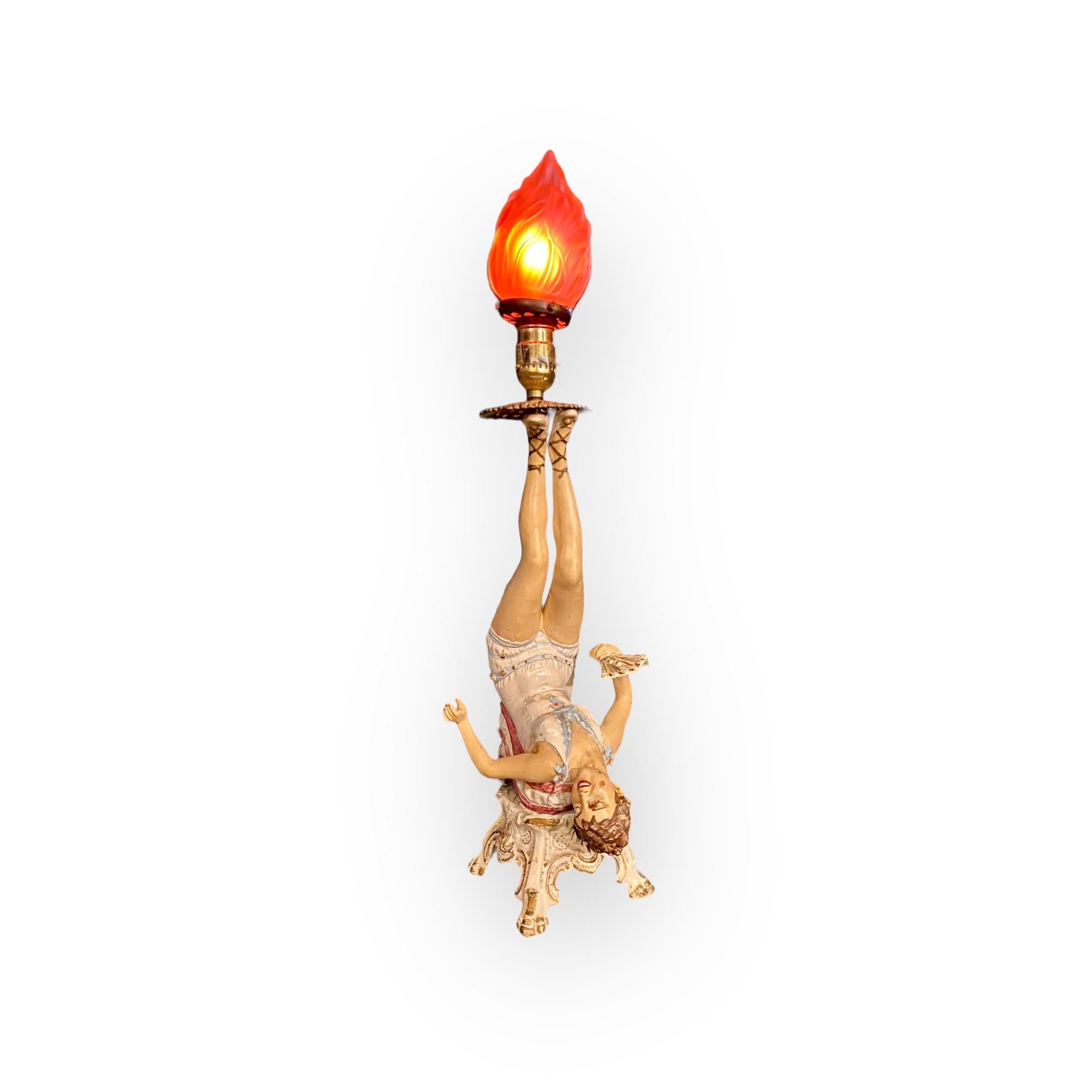 An unusual Art Nouveau Style early electric Figural Lamp, hand painted spelter metal of a maiden with fan reclining with her feet over her head and supporting a light socket with frosted glass flame shade, early 20th C. 
A unique, atmospheric piece