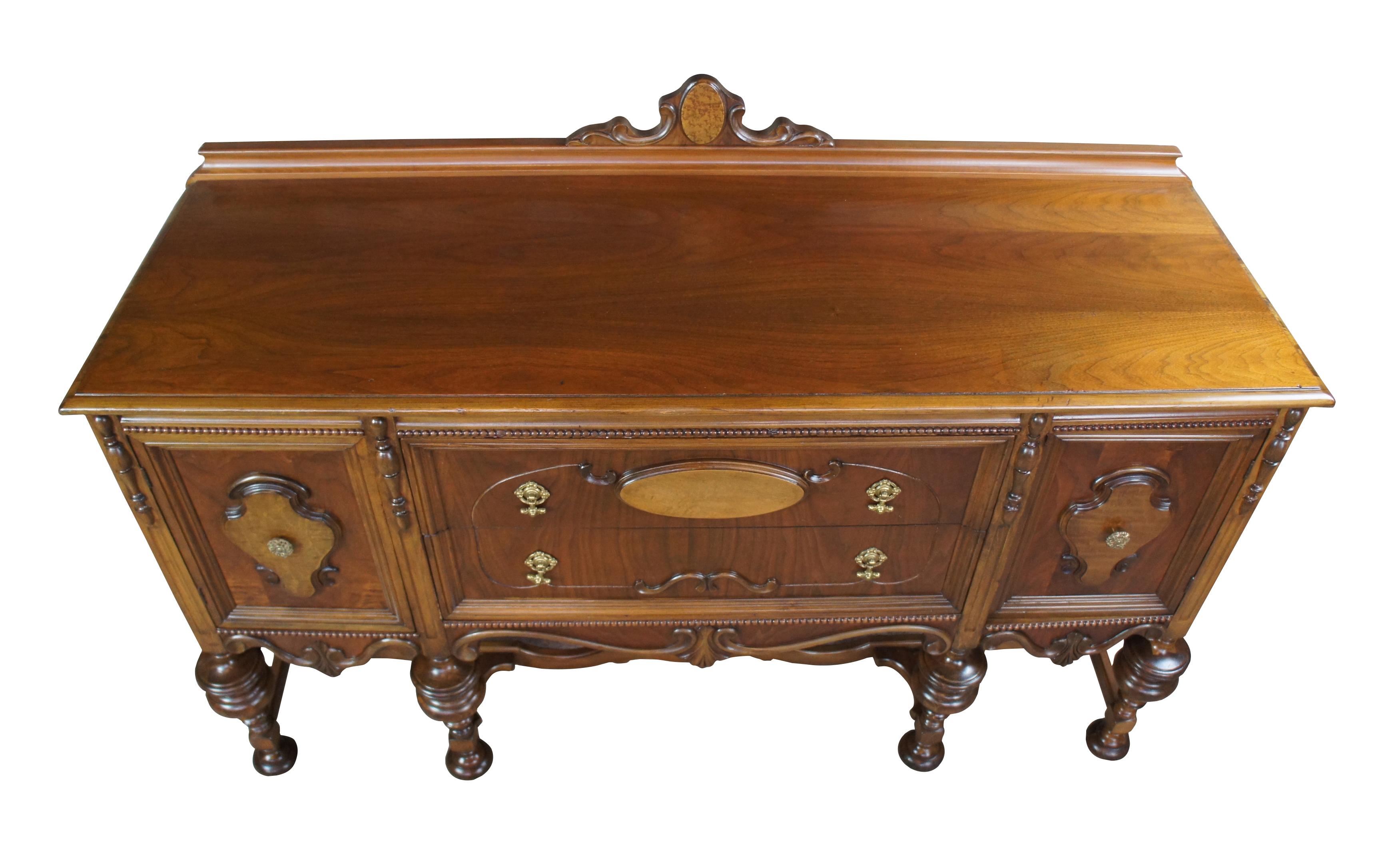 Turn of the century Jacobean or Elizabethan style sideboard. Made from walnut with robust turned legs and ornate trestle base, serpentine carved trim, beaded accents and burled panels. Features two long central drawers flanked by outer cabinets.
