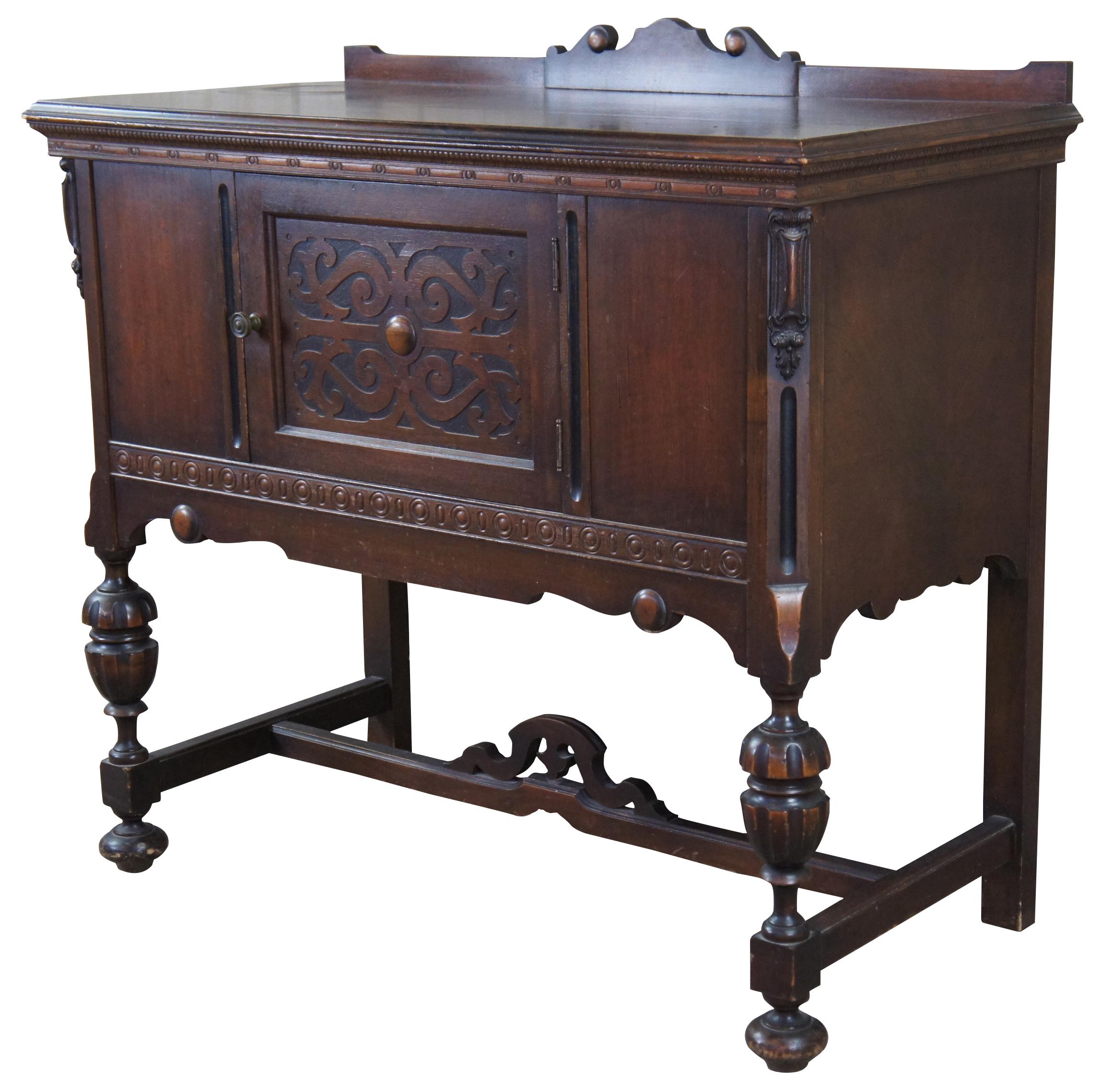 An early 20th century Jacobean Revival Server. Features a rectangular form with backsplash over baluster legs connected by an H stretcher and bun feet. Includes a large central storage area with scrolled door, beaded trim, medallions and gadrooning.