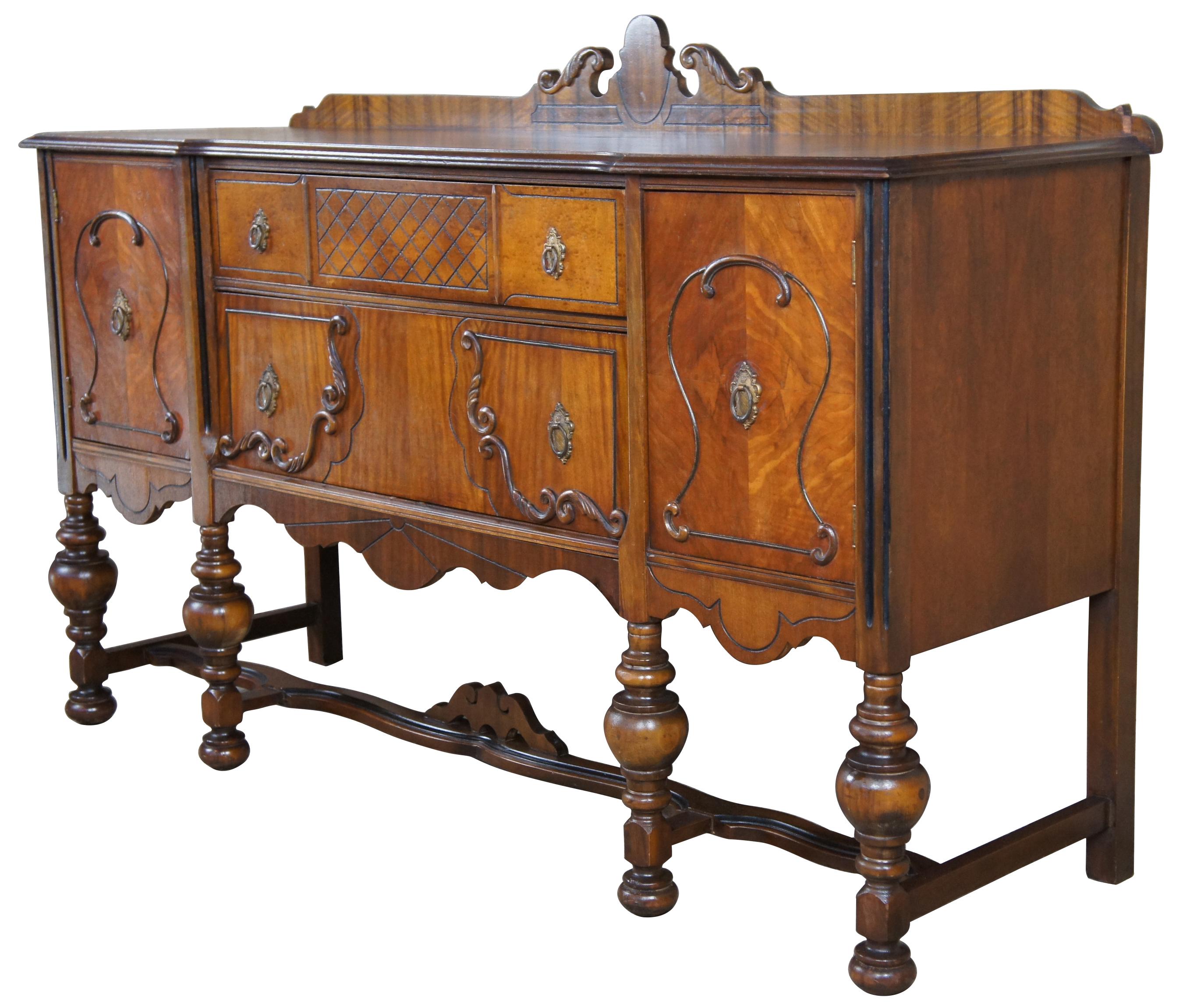Turn of the century Jacobean or Elizabethan style sideboard. Made from walnut with burled fron, robust turned legs, ornate serpentine trestle base, and scolled accents. Features two long central drawers flanked by outer cabinets. Measure: