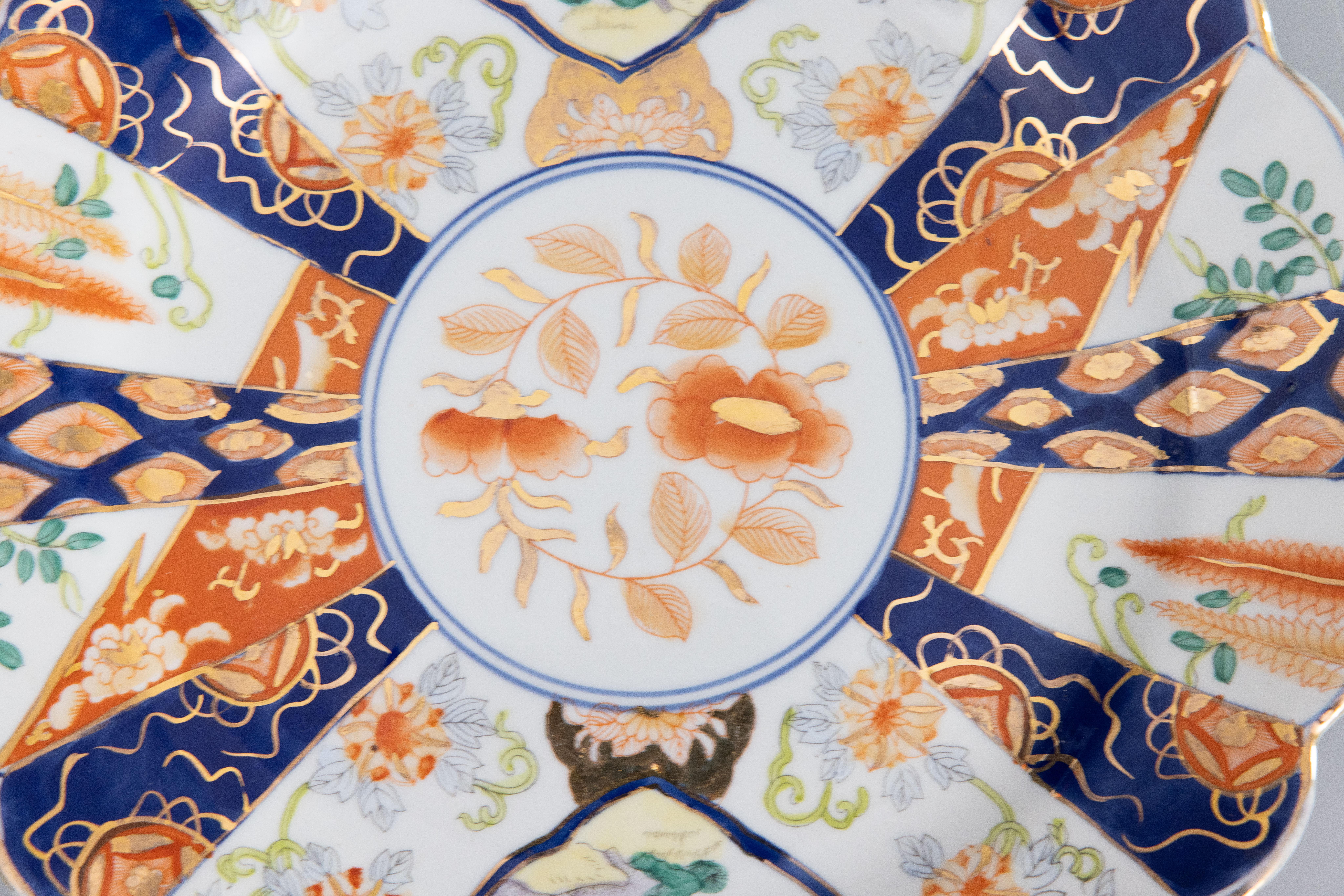 A gorgeous Early 20th-Century Japanese Imari porcelain charger with a hand painted floral design in the traditional Imari colors and gold accents. This fine large plate has lovely gilt scalloped edges and is quite heavy, weighing over 3 lbs. It