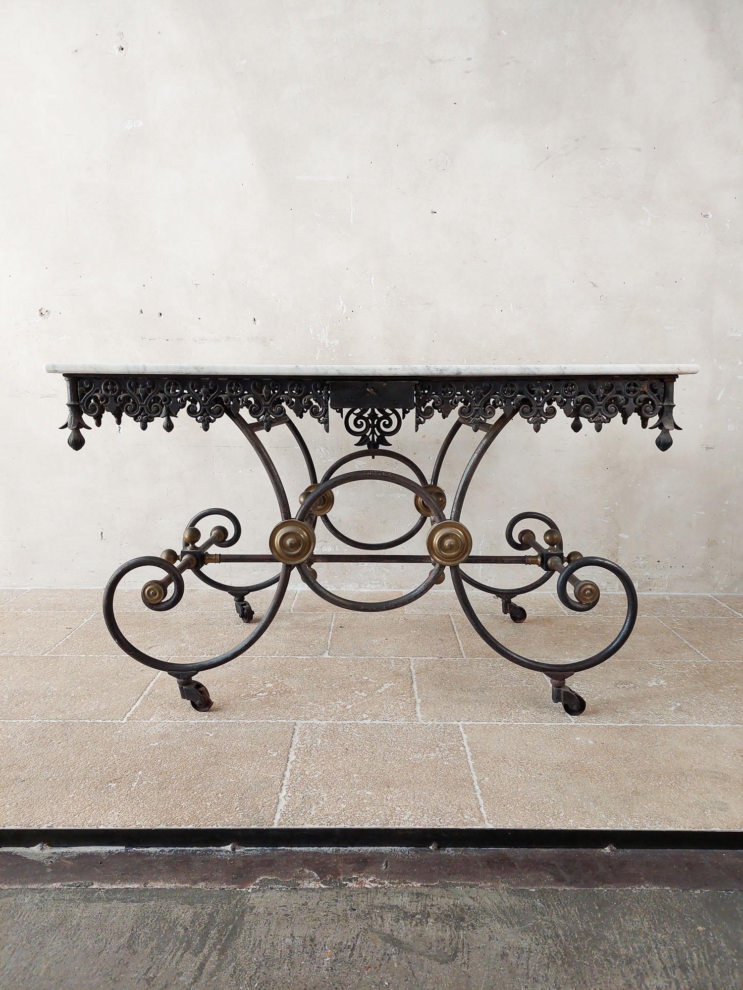 Antique luxury butcher’s table with Carrara marble top from the early 1900s. The base of this butcher’s display table is made of wrought iron and cast iron in a beautiful curl with a beautiful edge and drawer. The table has bronze details as a