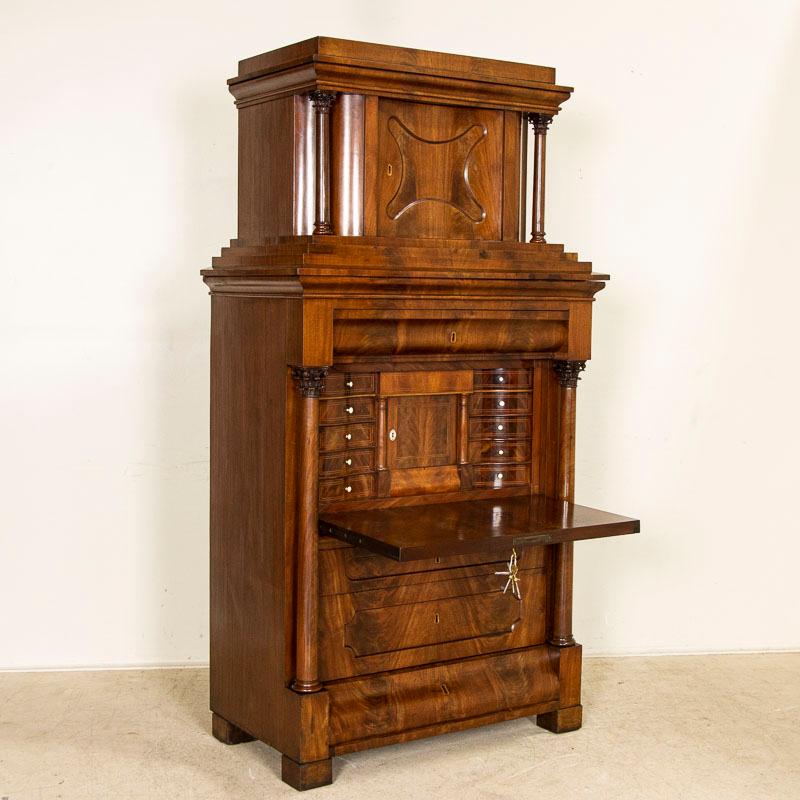 Rich dark wood and stately lines define this handsome Biedermeier drop front secretary from Germany. Note the concave curve of the upper cabinet door and beautiful mahogany grain pattern that attracts the eye to the entire front view of this