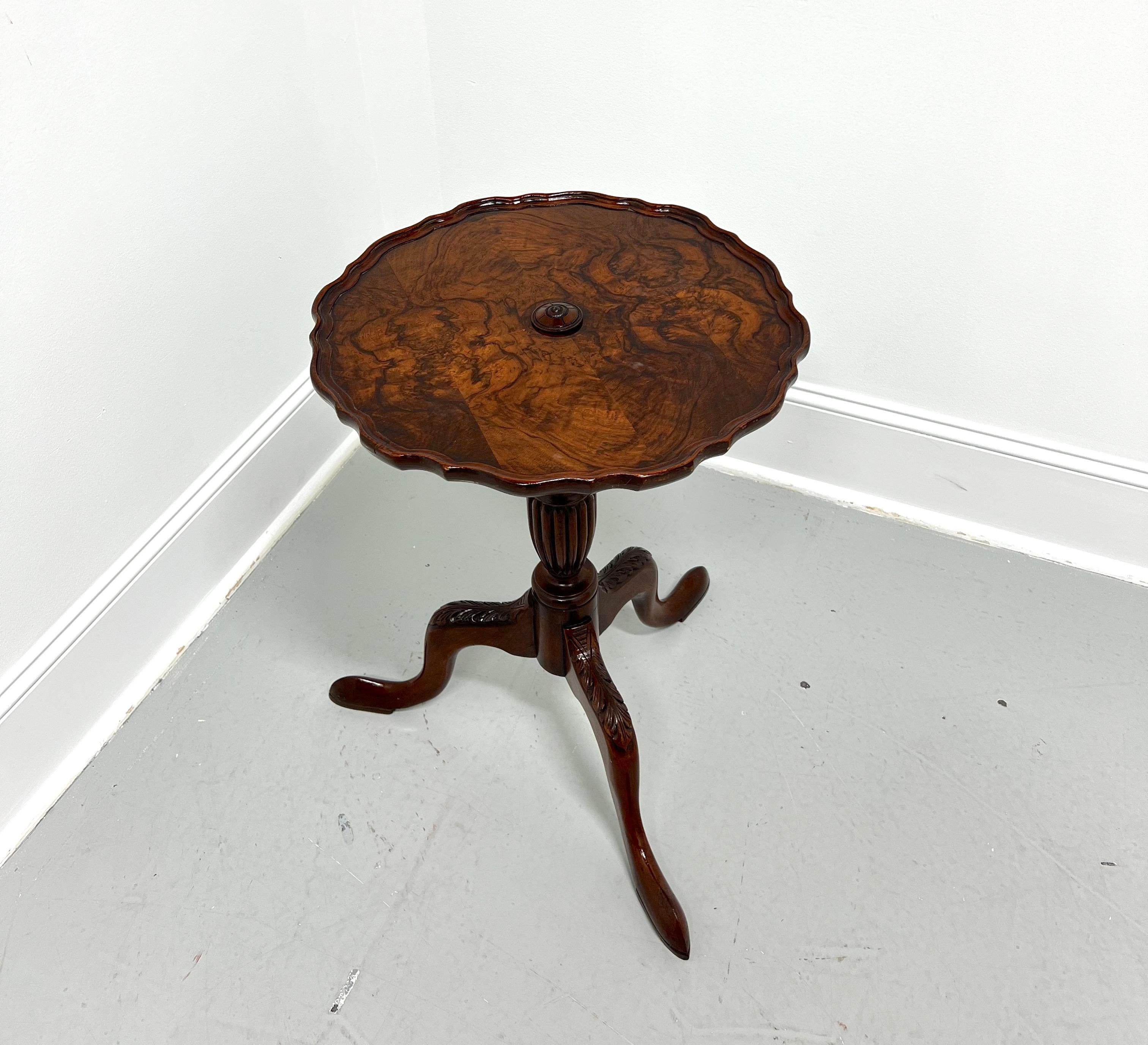 An antique petite pie crust table in the Chippendale style, unbranded. Solid mahogany with inlaid burl walnut top, a mahogany scalloped edge and center adornment to the top, turned & fluted pedestal base, three legs with acanthus leaf carved knees,