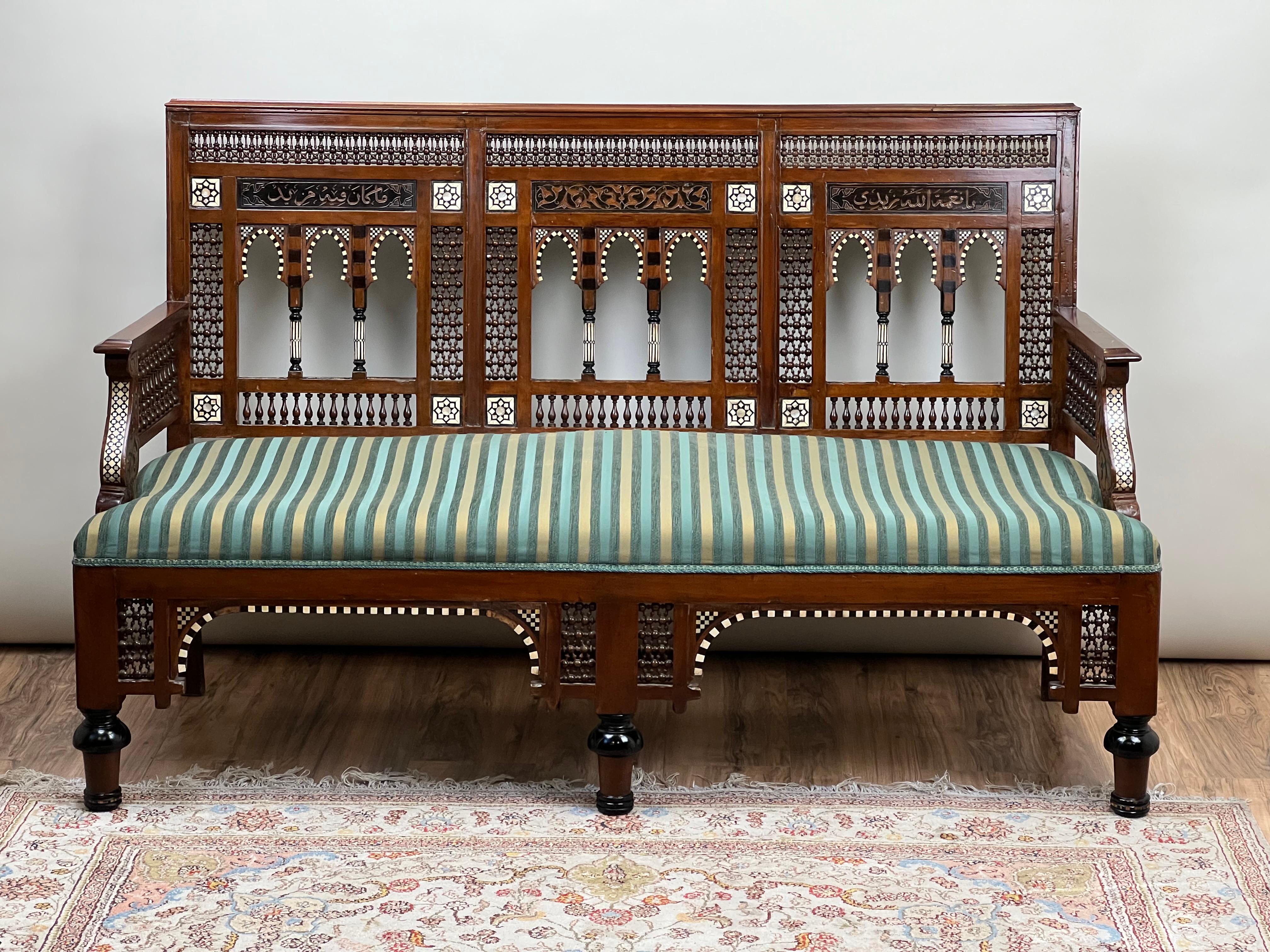 Ce superbe canapé mauresque du début du XXe siècle est un exemple remarquable d'artisanat complexe et de design exotique. Construit en bois dur, le cadre présente un ensemble éblouissant d'incrustations d'os et de nacre dans des motifs géométriques